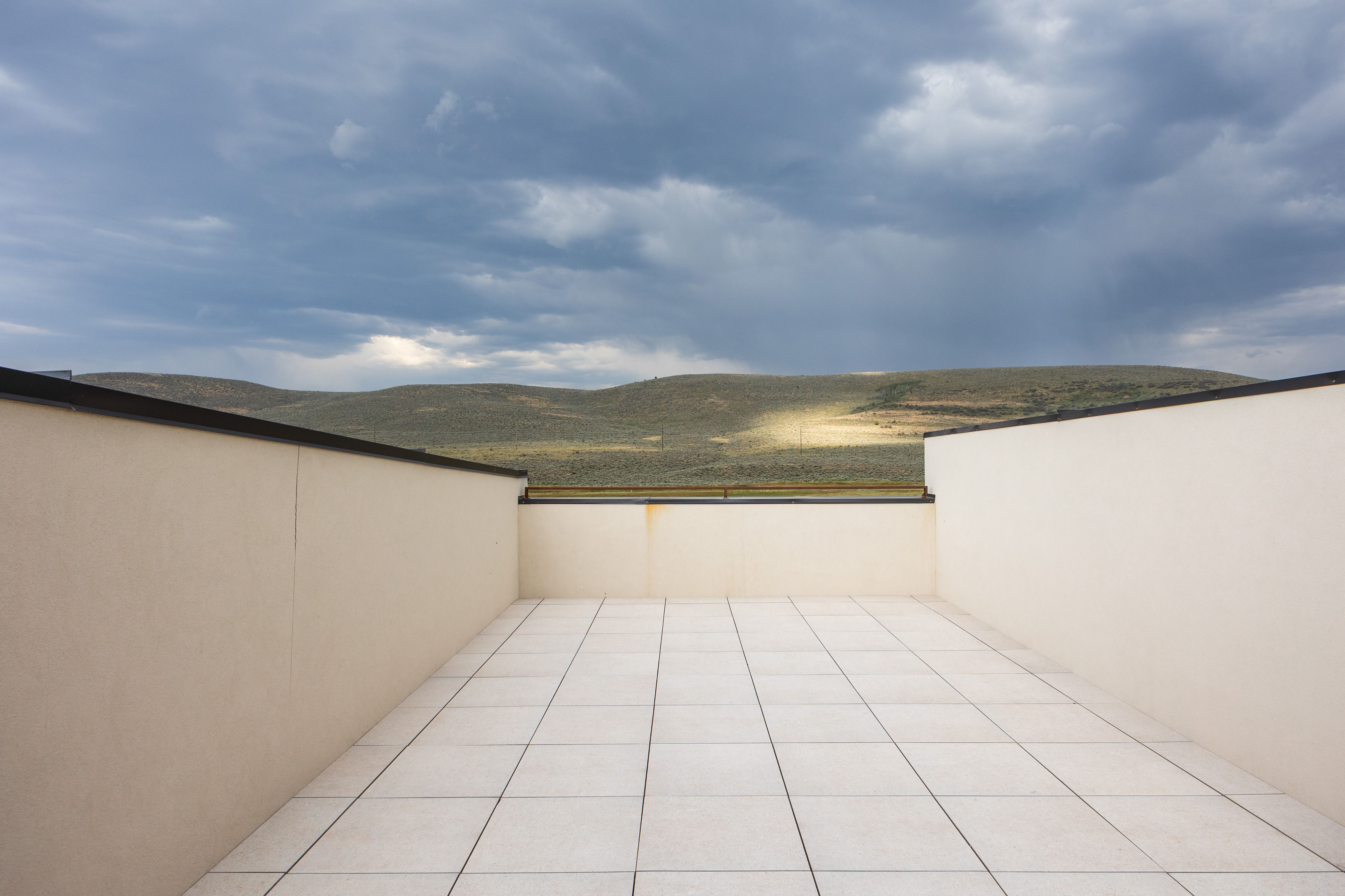 Rooftop terrace with light-toned rectangular tile flooring and low perimeter walls