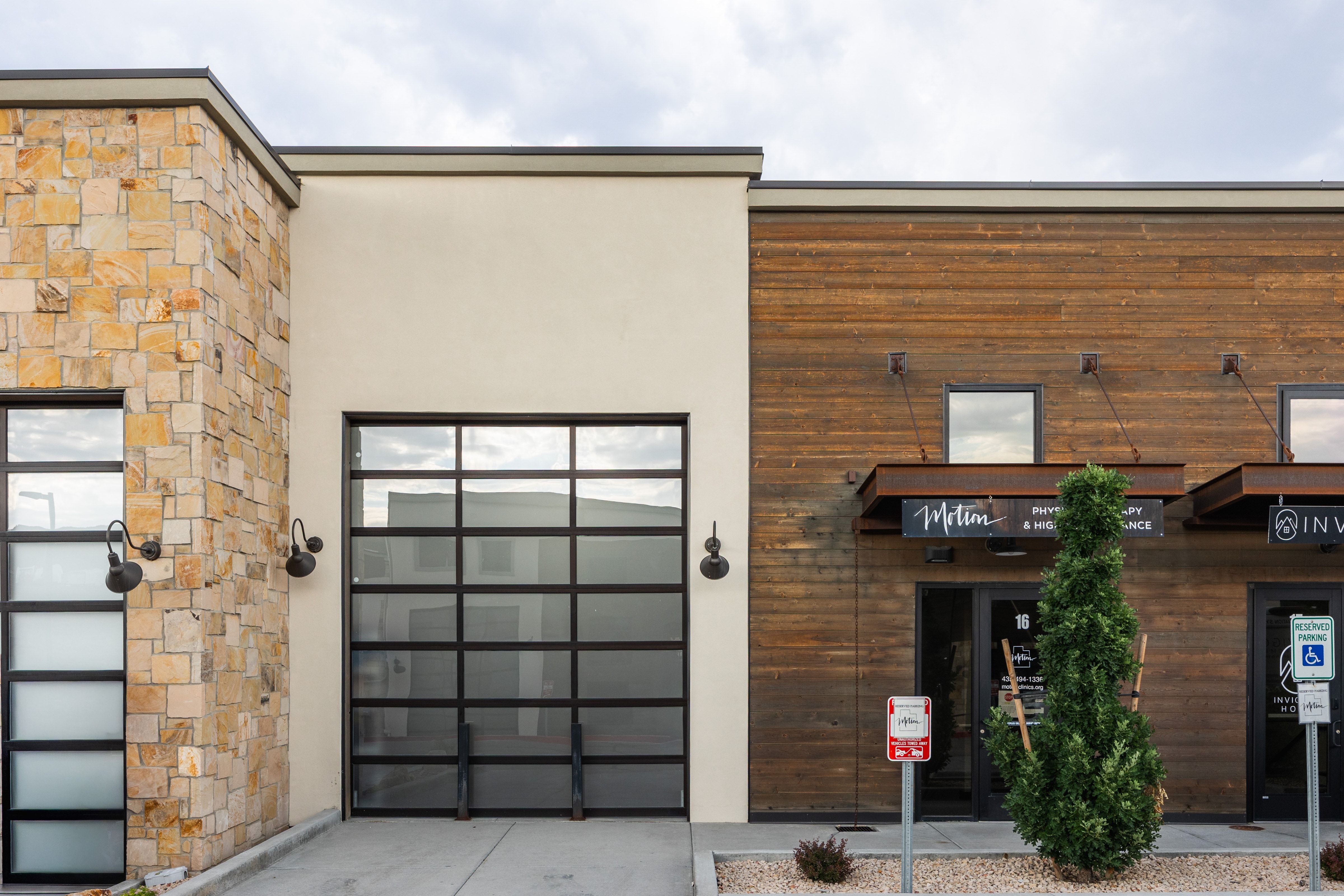 Modern commercial facade featuring a stone veneer accent wall, horizontal wood siding, and stucco finishes