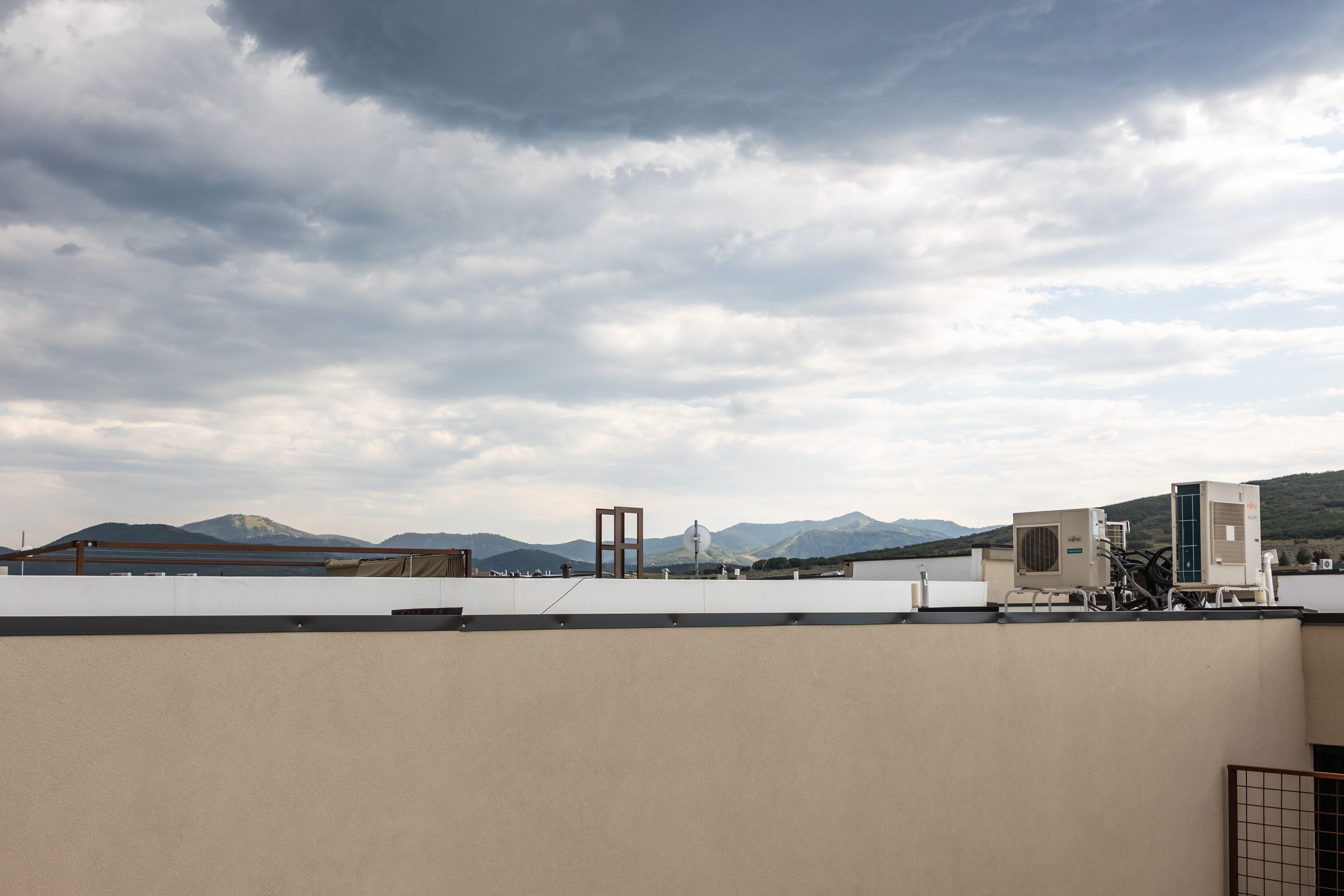 Rooftop terrace with stucco parapet, showcasing distant mountains and open sky
