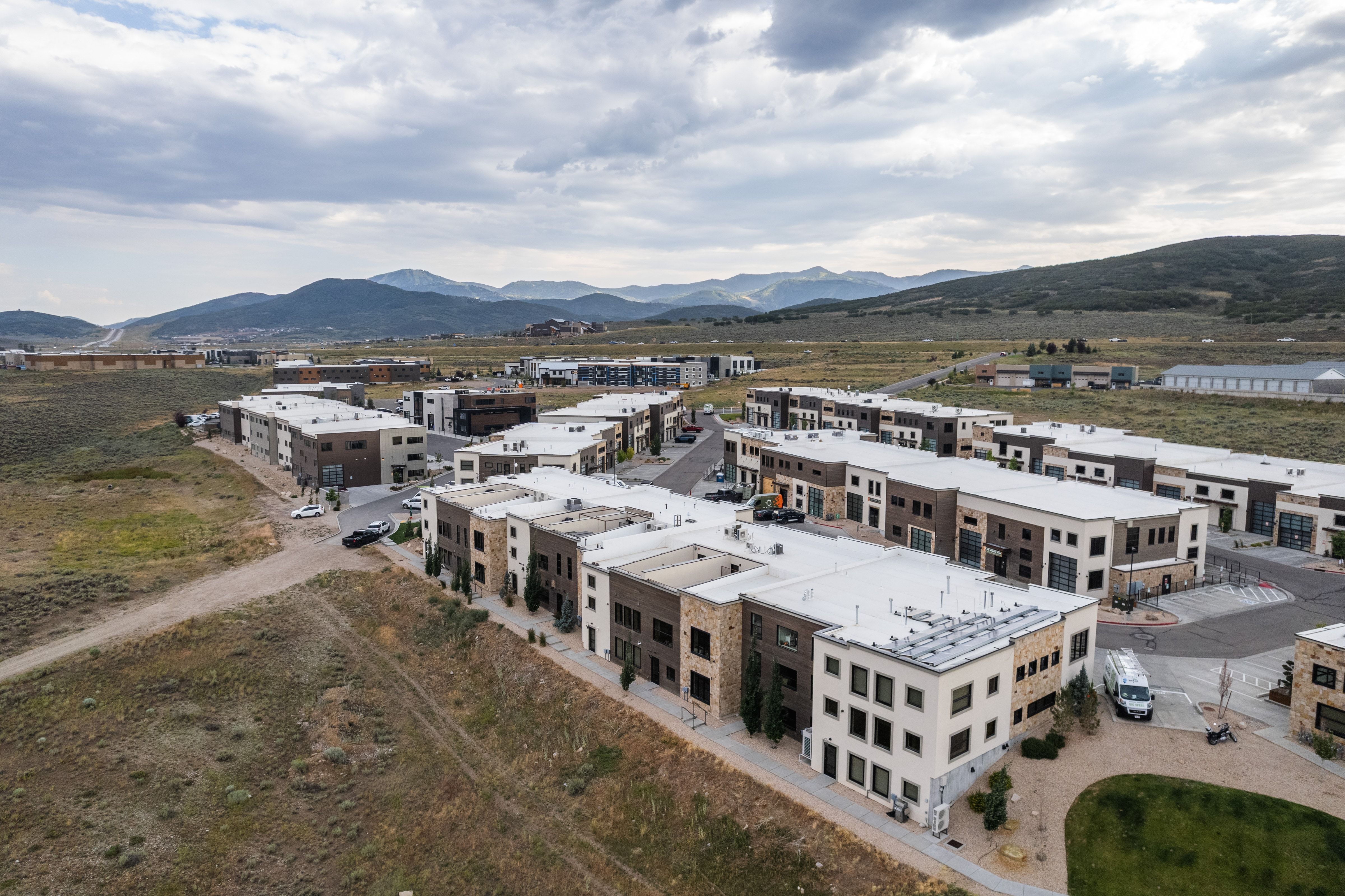 Modern multi-level townhome-style residences featuring varied facades with stone and panel accents, flat roofs, and integrated garages
