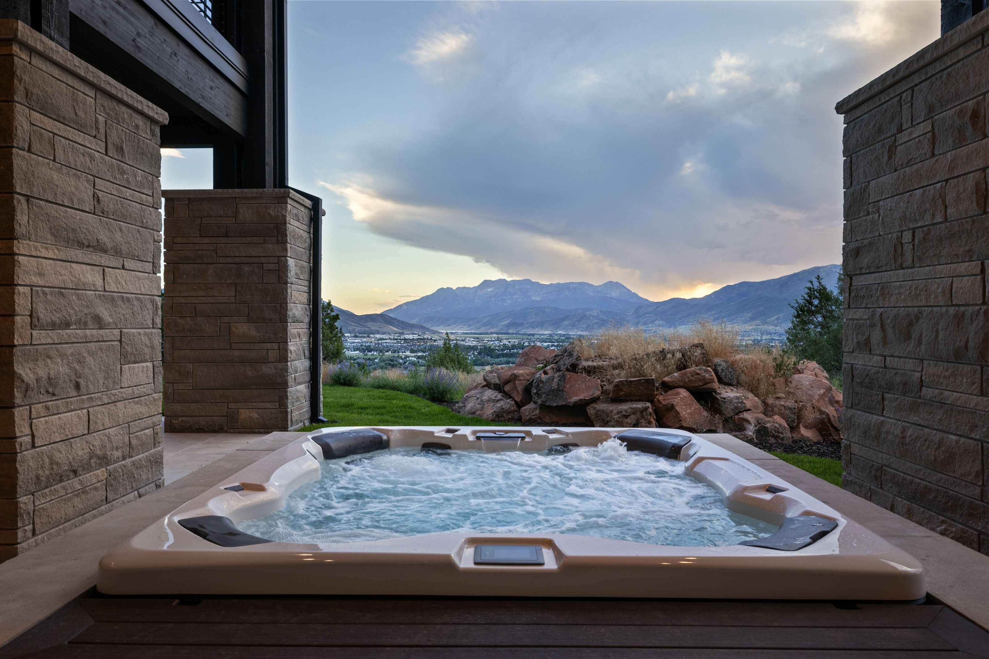 Outdoor hot tub with textured stone columns and a wood-finish deck