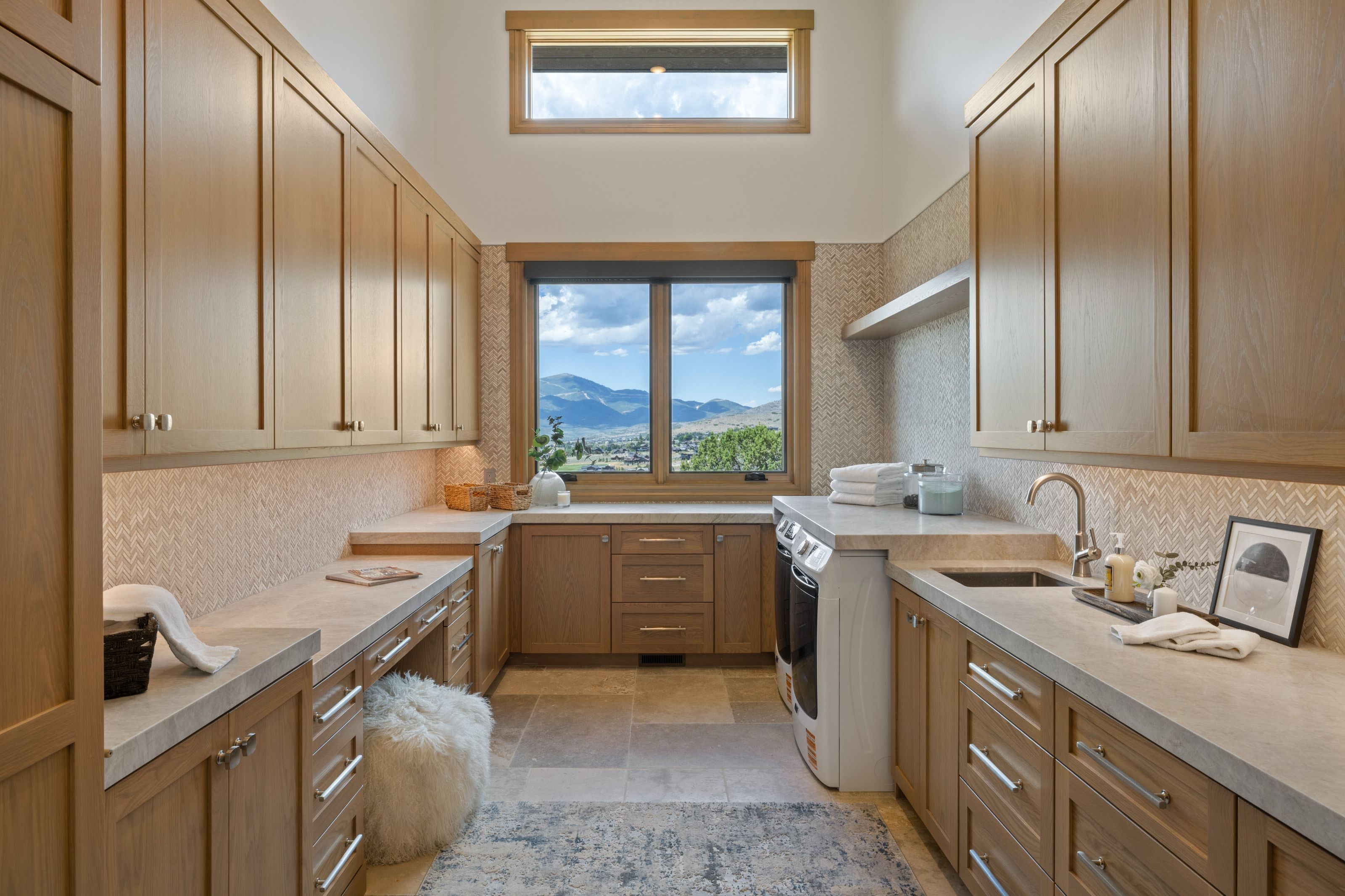 Spacious utility room featuring extensive built-in cabinetry, durable countertops, and a window framing mountainous scenery