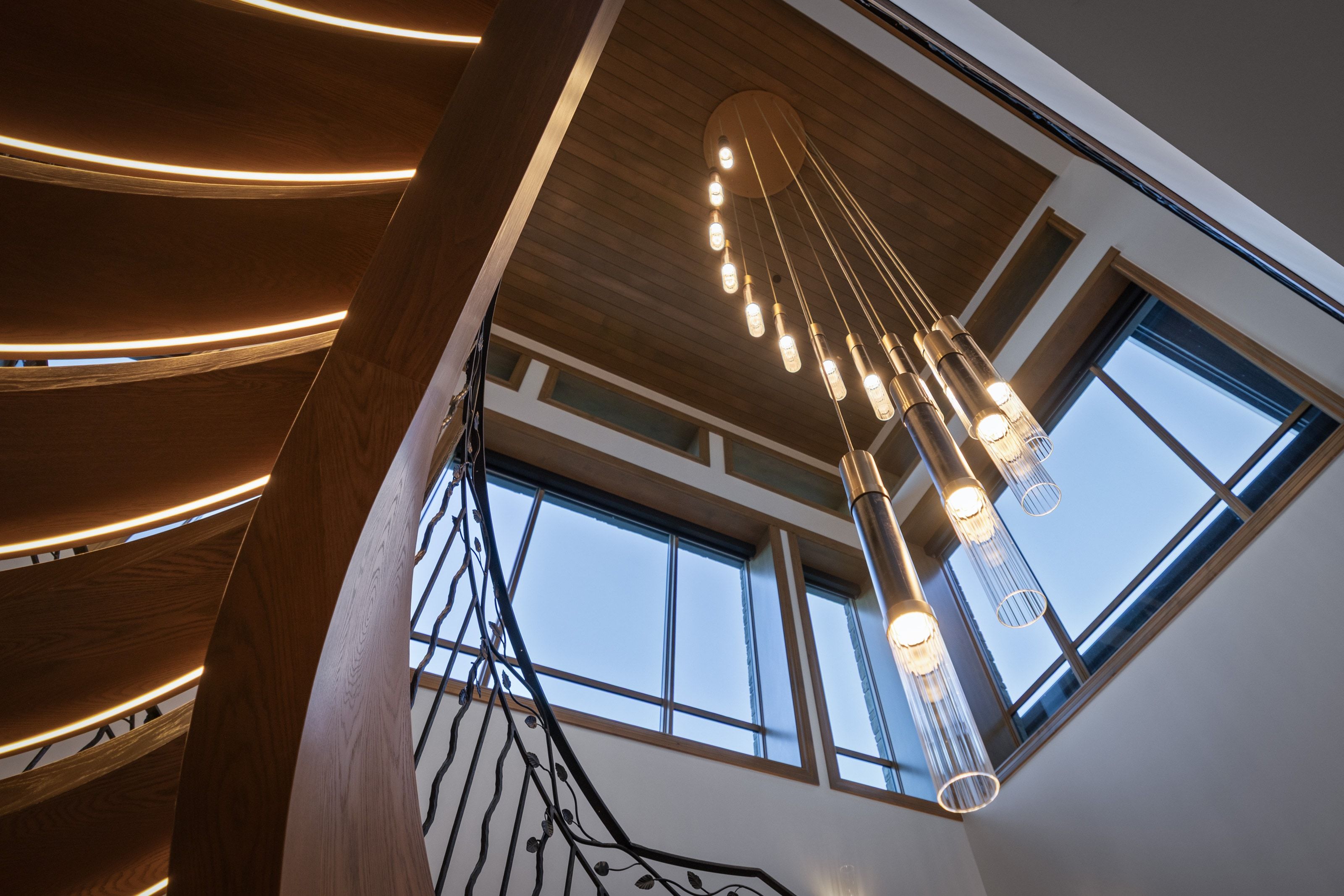 Grand entry featuring a custom spiral staircase with integrated lighting, wood-finish treads, and an ornate wrought iron railing