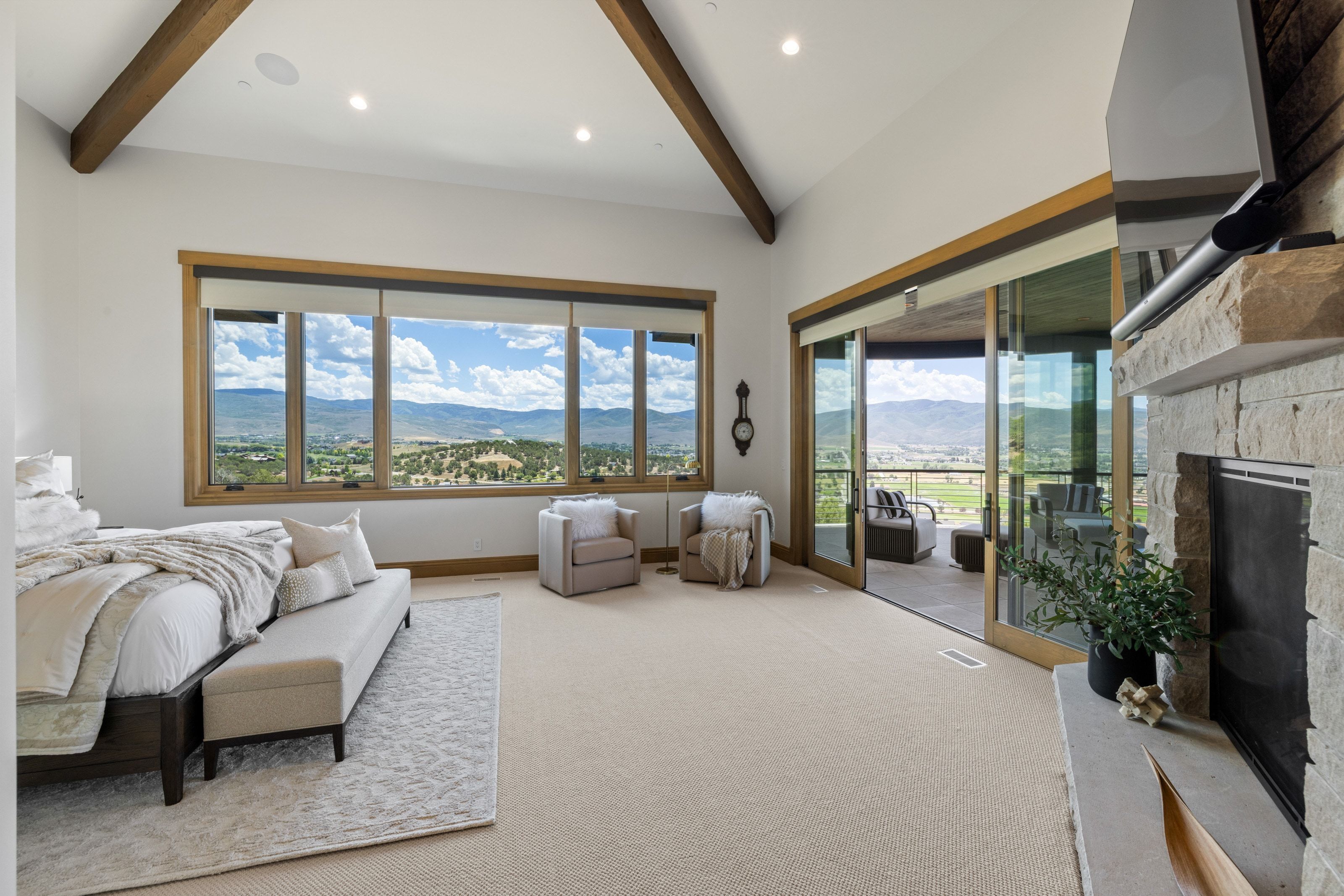 Spacious room featuring vaulted ceilings with exposed wood beams and recessed lighting