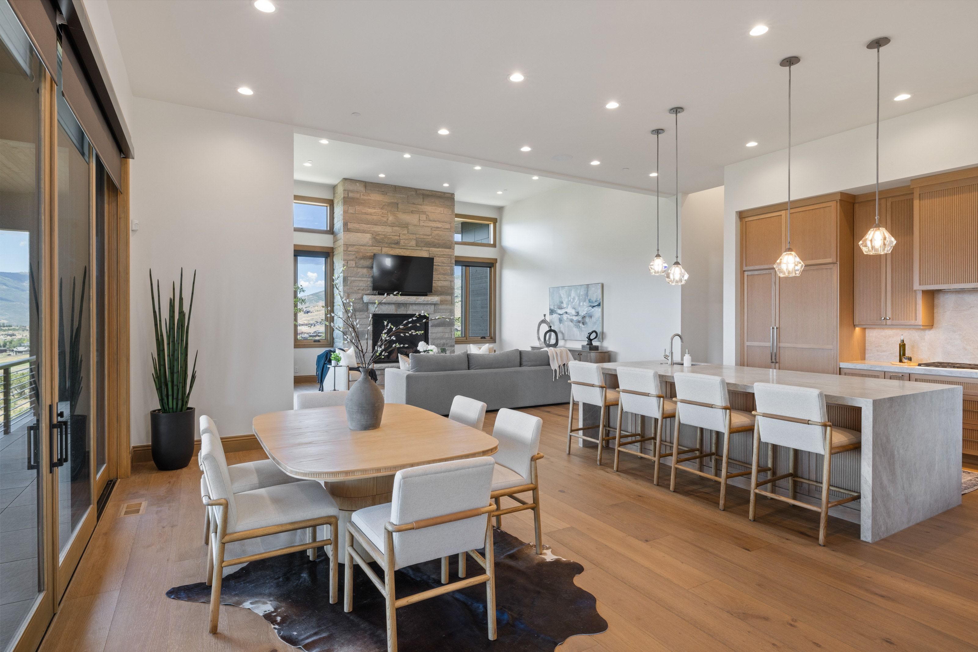 Open-concept living area featuring wood-finish flooring, a stone fireplace, and large sliding glass doors