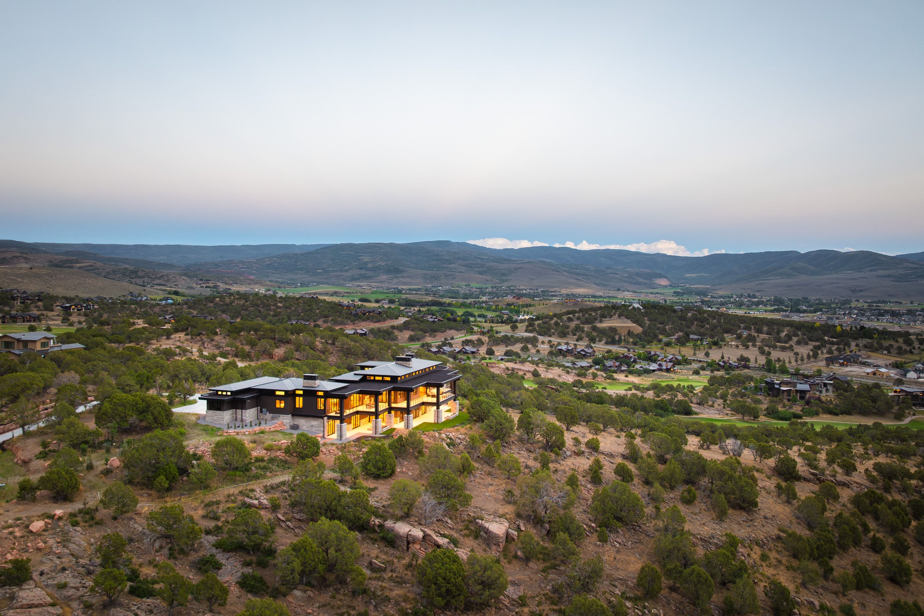 Modern architectural residence with multiple levels, extensive exterior lighting, and large windows