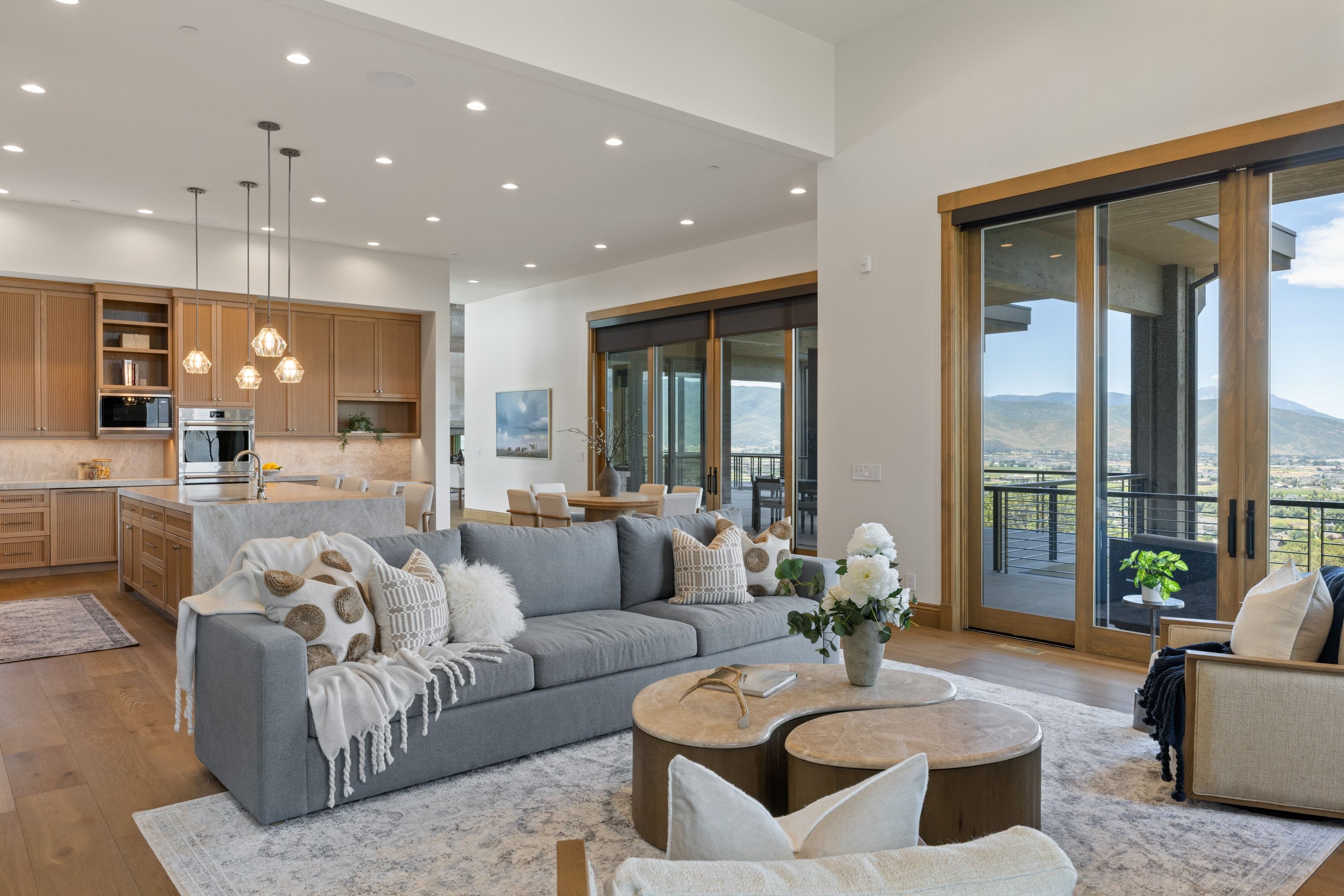 Open-concept living area featuring wood-finish flooring, recessed lighting, and a kitchen with light wood cabinetry and a central island