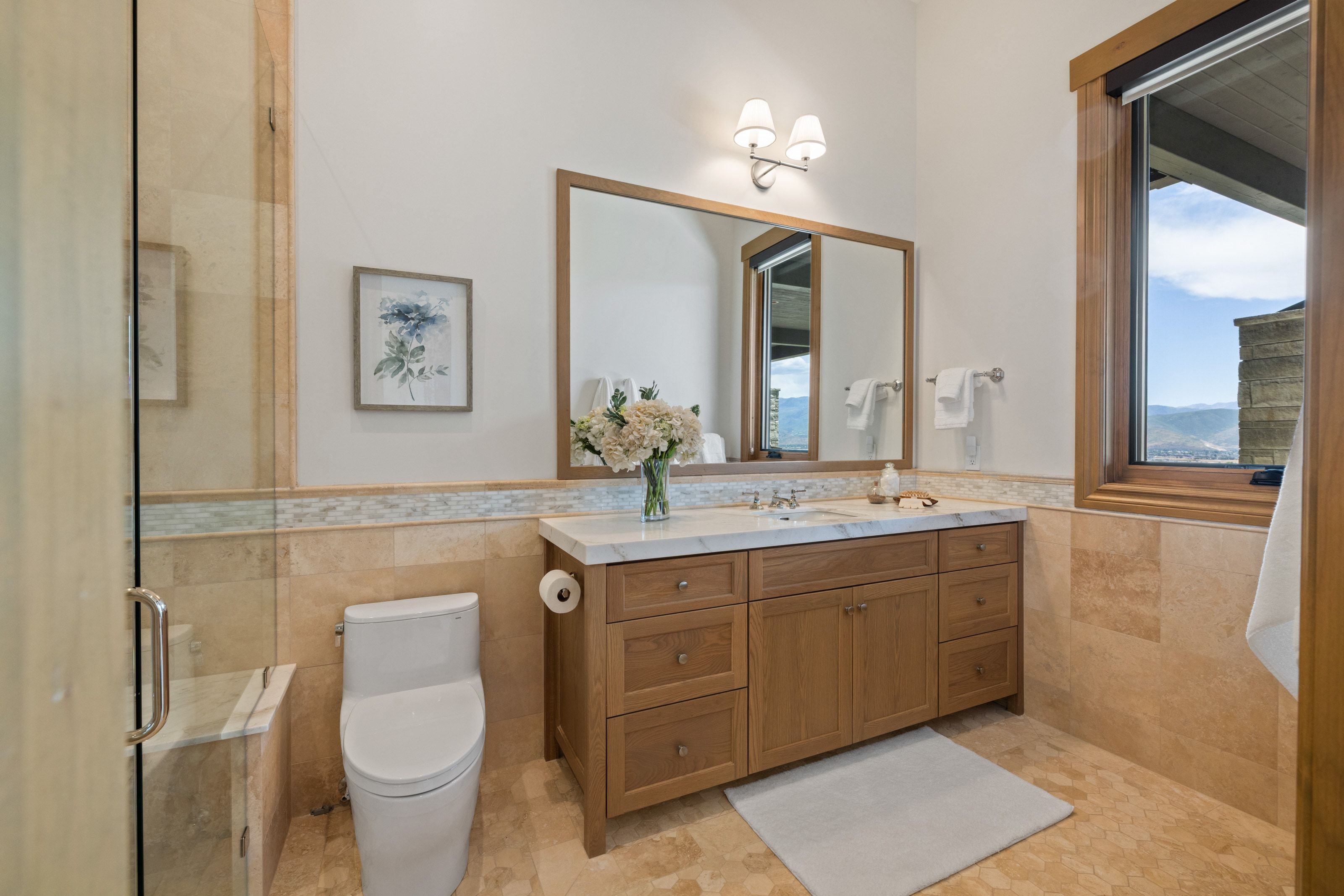Bathroom featuring a wood vanity with a white countertop, framed mirror, and dual wall sconces