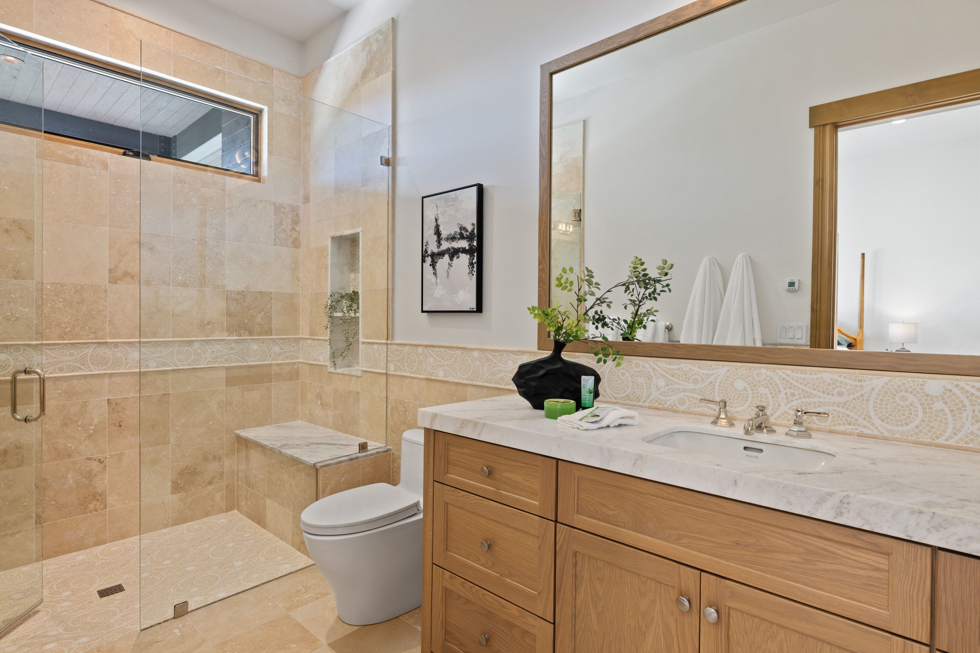 Spacious bathroom featuring a glass-enclosed shower with full tile surround, integrated bench, and niche shelving