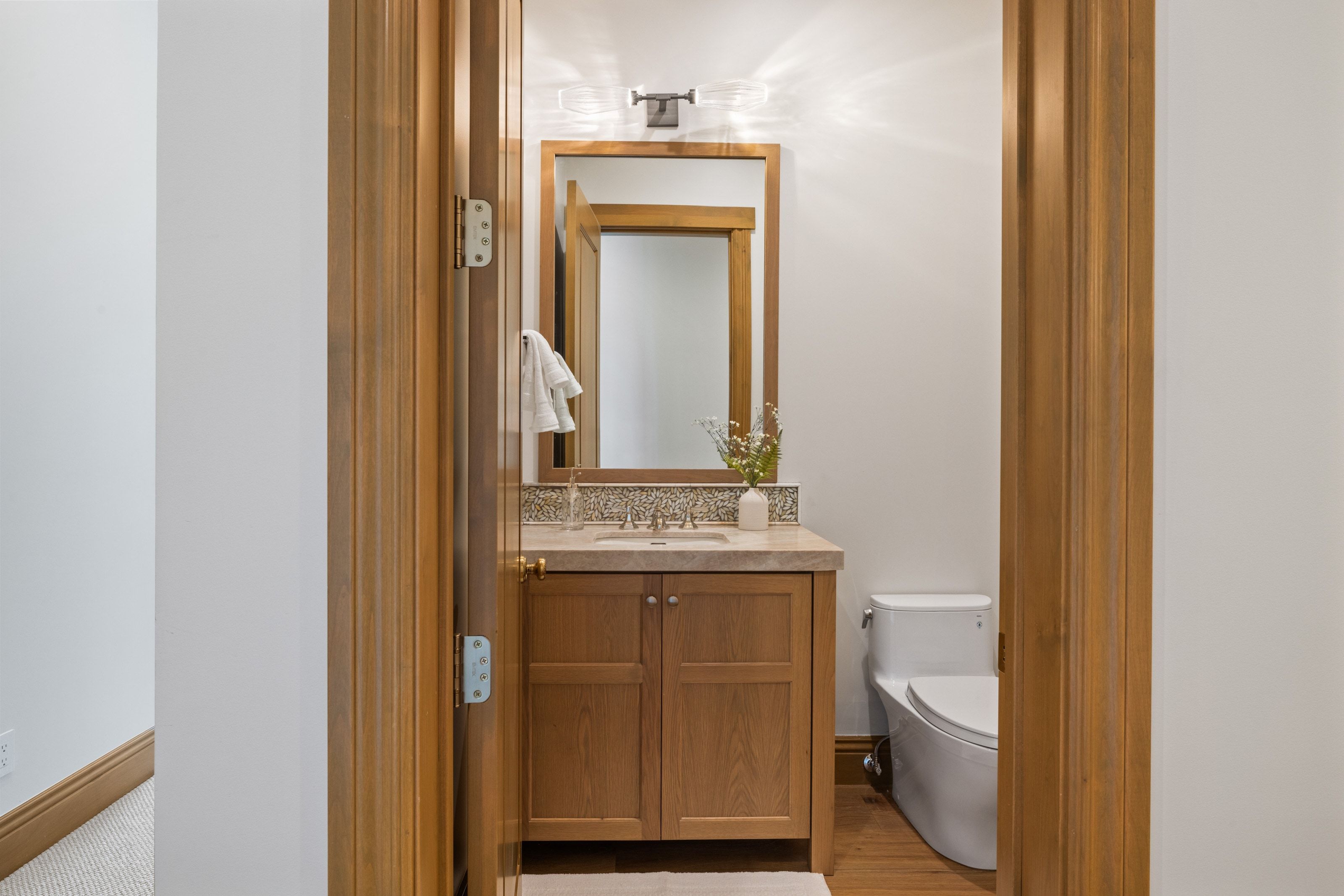 Full vanity with wood cabinetry, stone countertop, and integrated sink