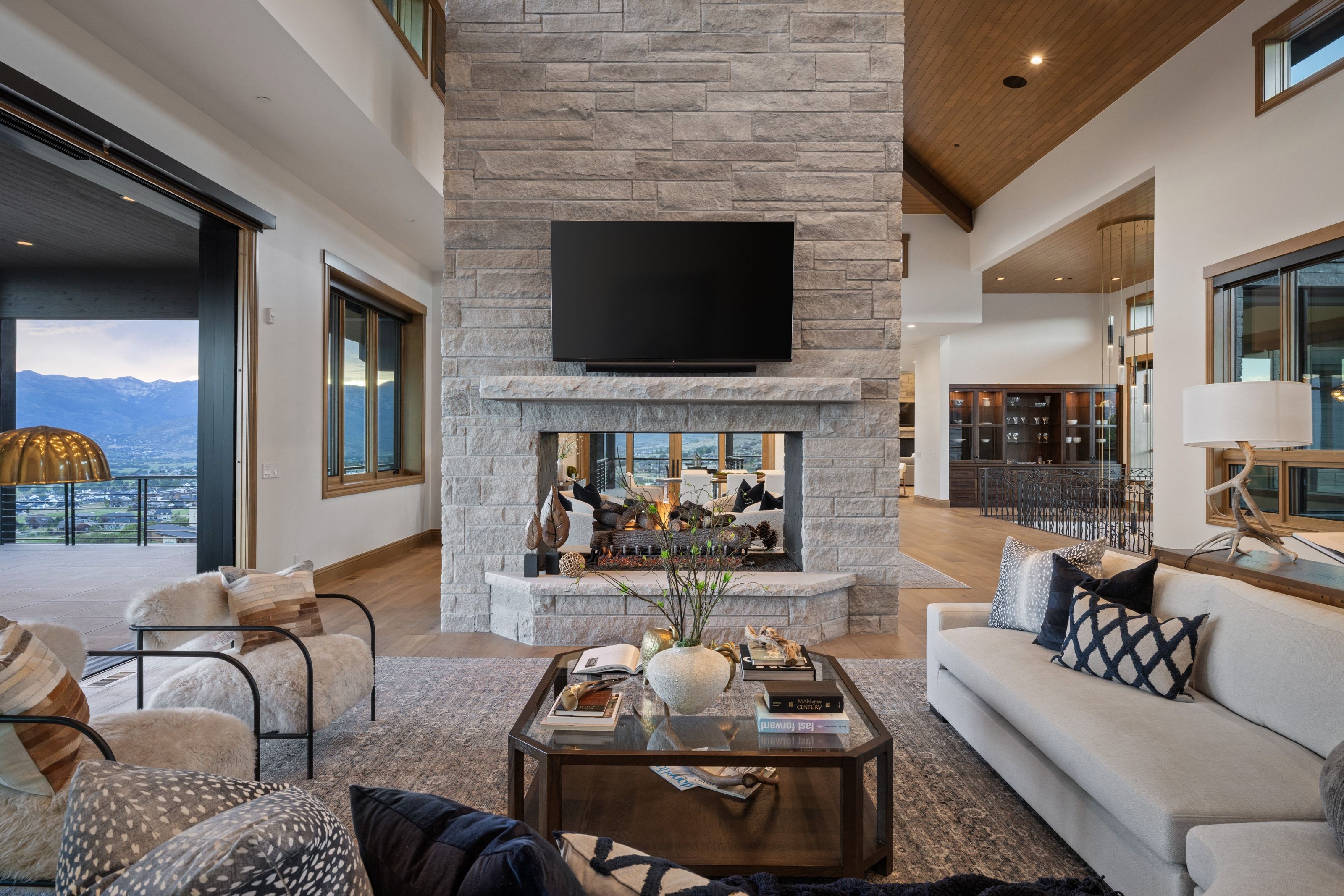 Stone-clad fireplace with hearth, integrated television, and open flame feature