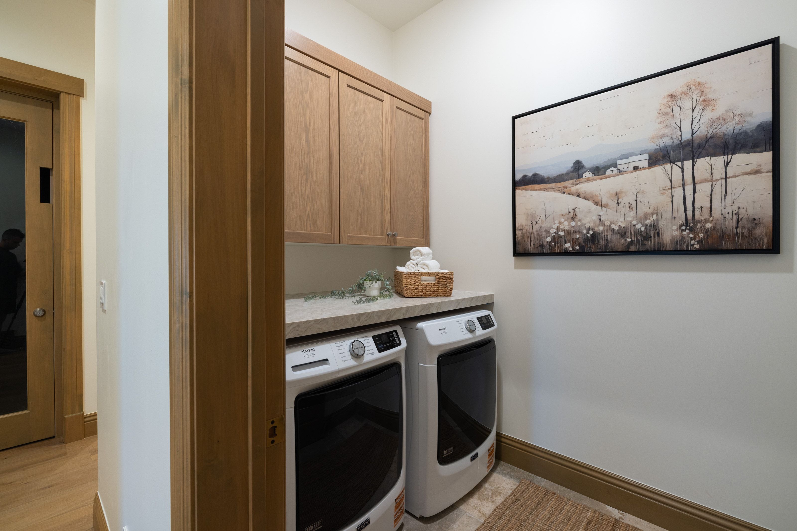 Dedicated laundry area featuring a stone-look countertop, light wood-finish cabinetry, and tiled flooring