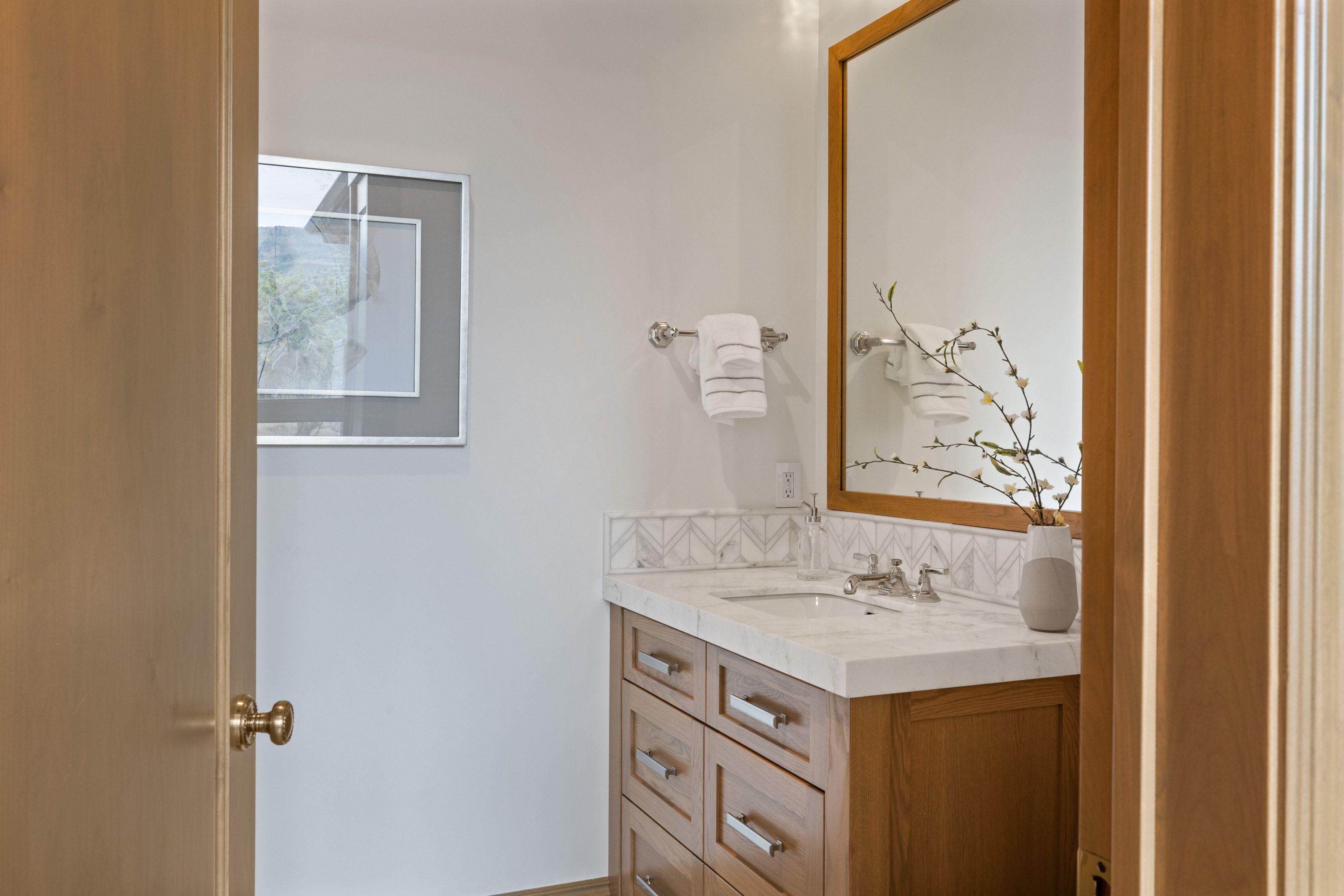 Vanity featuring a light wood-finish cabinet with drawers, a stone countertop, a rectangular undermount sink, and a framed mirror