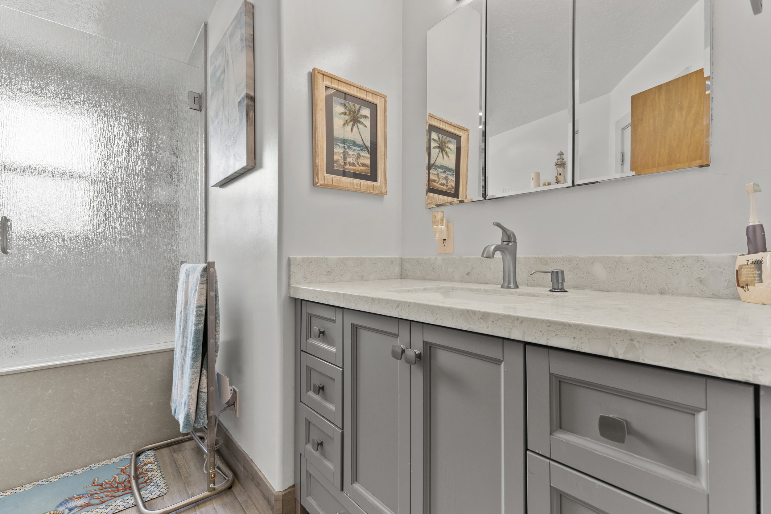 Bathroom vanity with a light gray countertop, undermount sink, and brushed nickel faucet