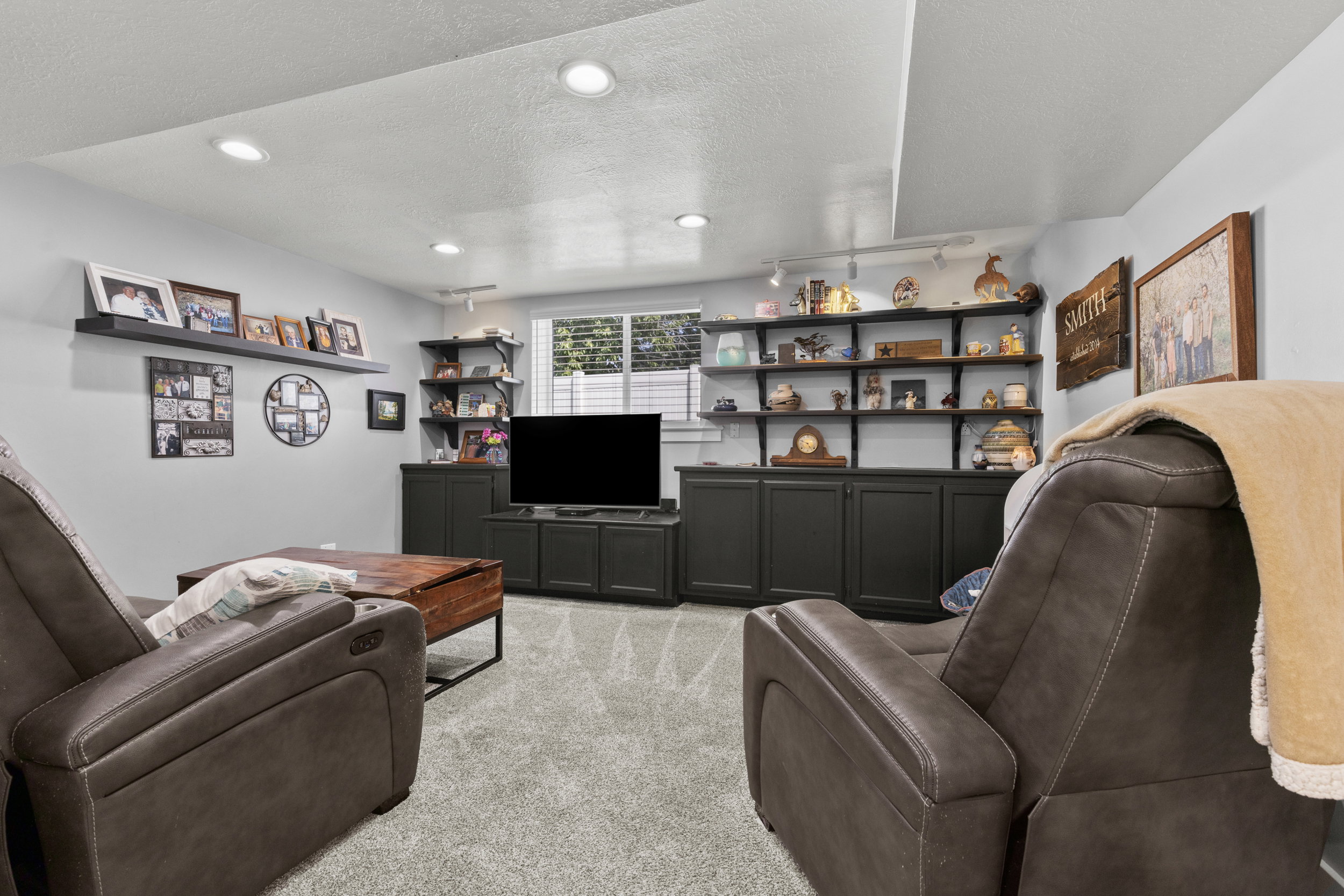 Recessed lighting illuminates a carpeted room featuring extensive built-in shelving and cabinetry