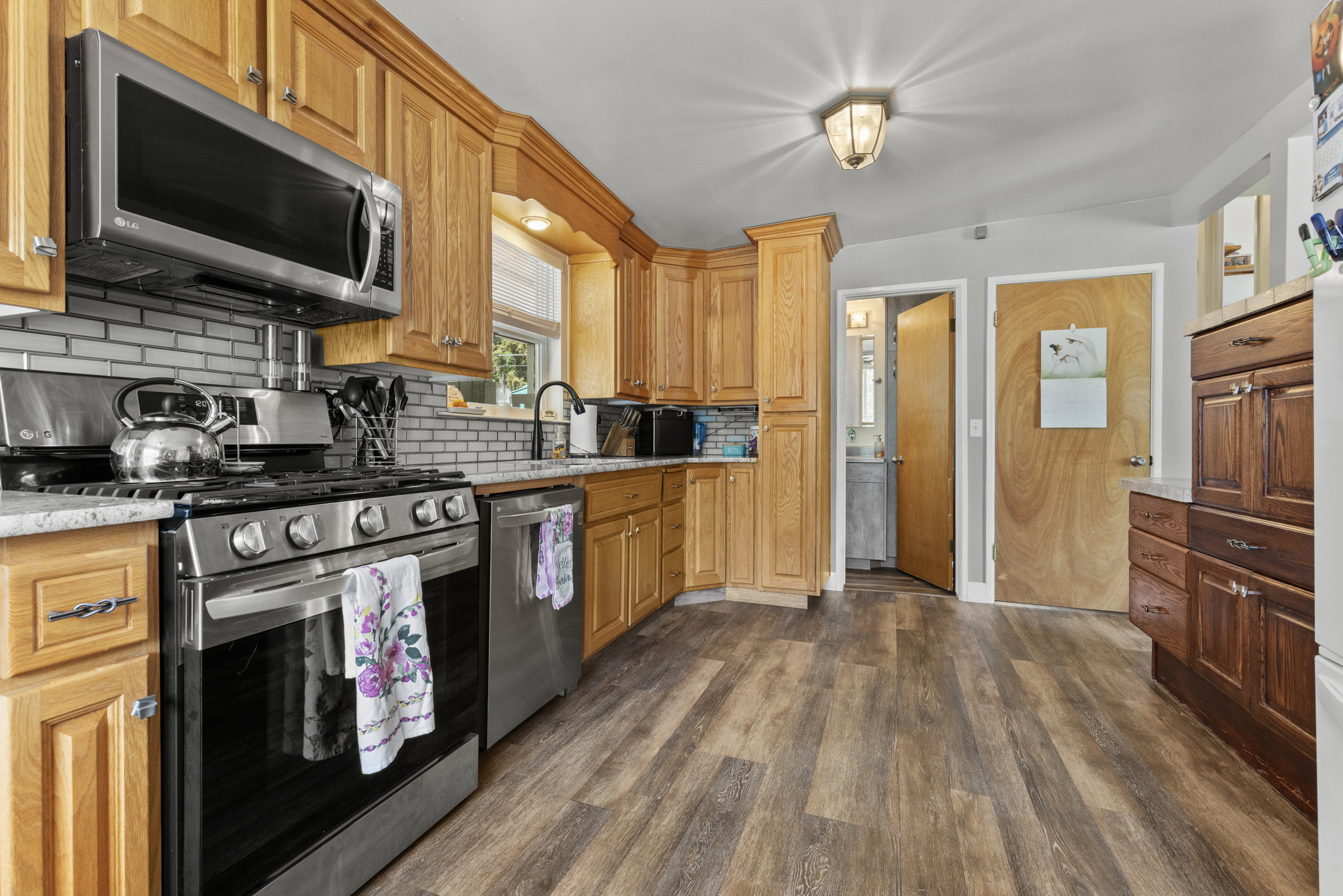 Kitchen featuring wood-finish flooring, light wood cabinetry, and stainless steel appliances