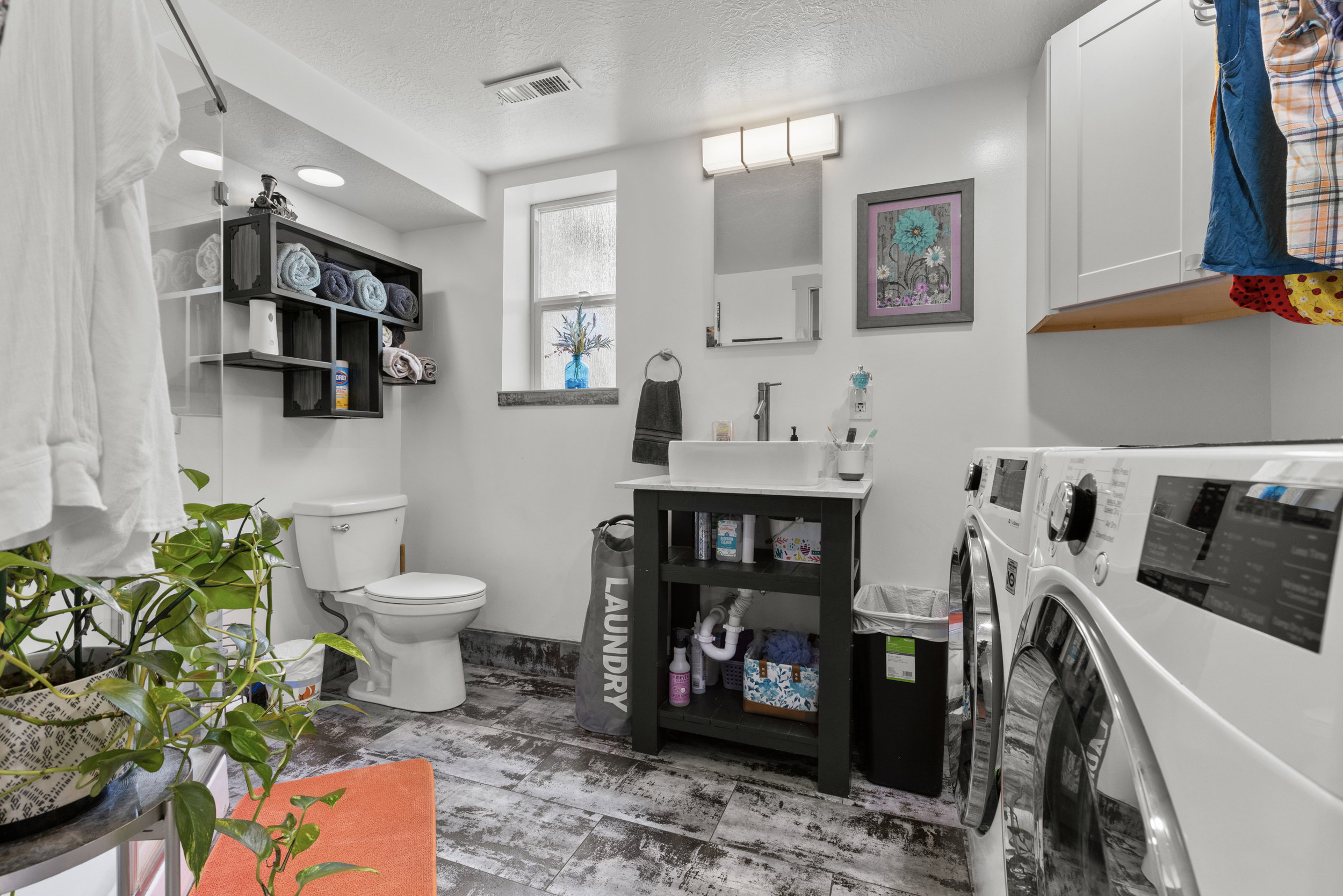 Laundry room featuring a white vessel sink, dark wood-finish vanity, and a washer and dryer set