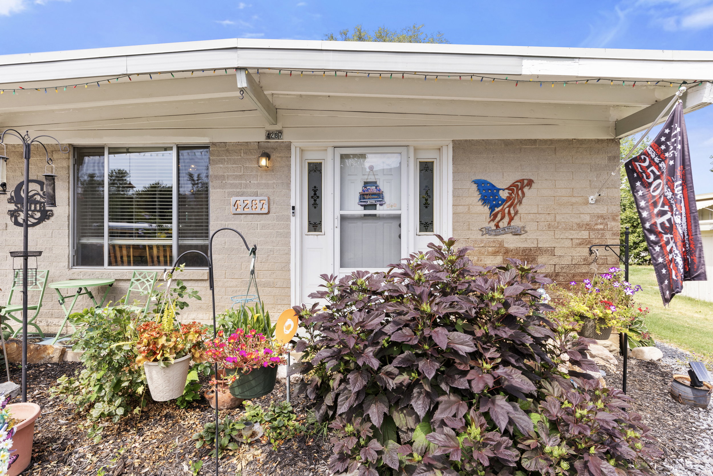 Brick facade entry featuring a white storm door and a single-pane window with horizontal blinds