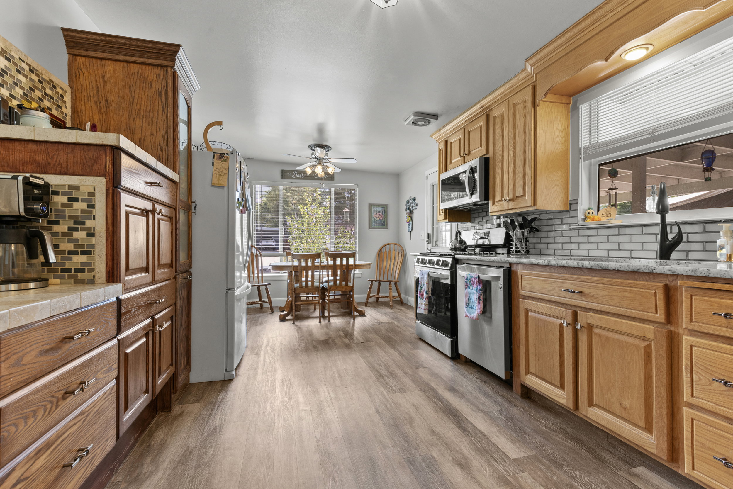Kitchen featuring wood-finish flooring, light wood cabinetry, stainless steel appliances, and a subway tile backsplash
