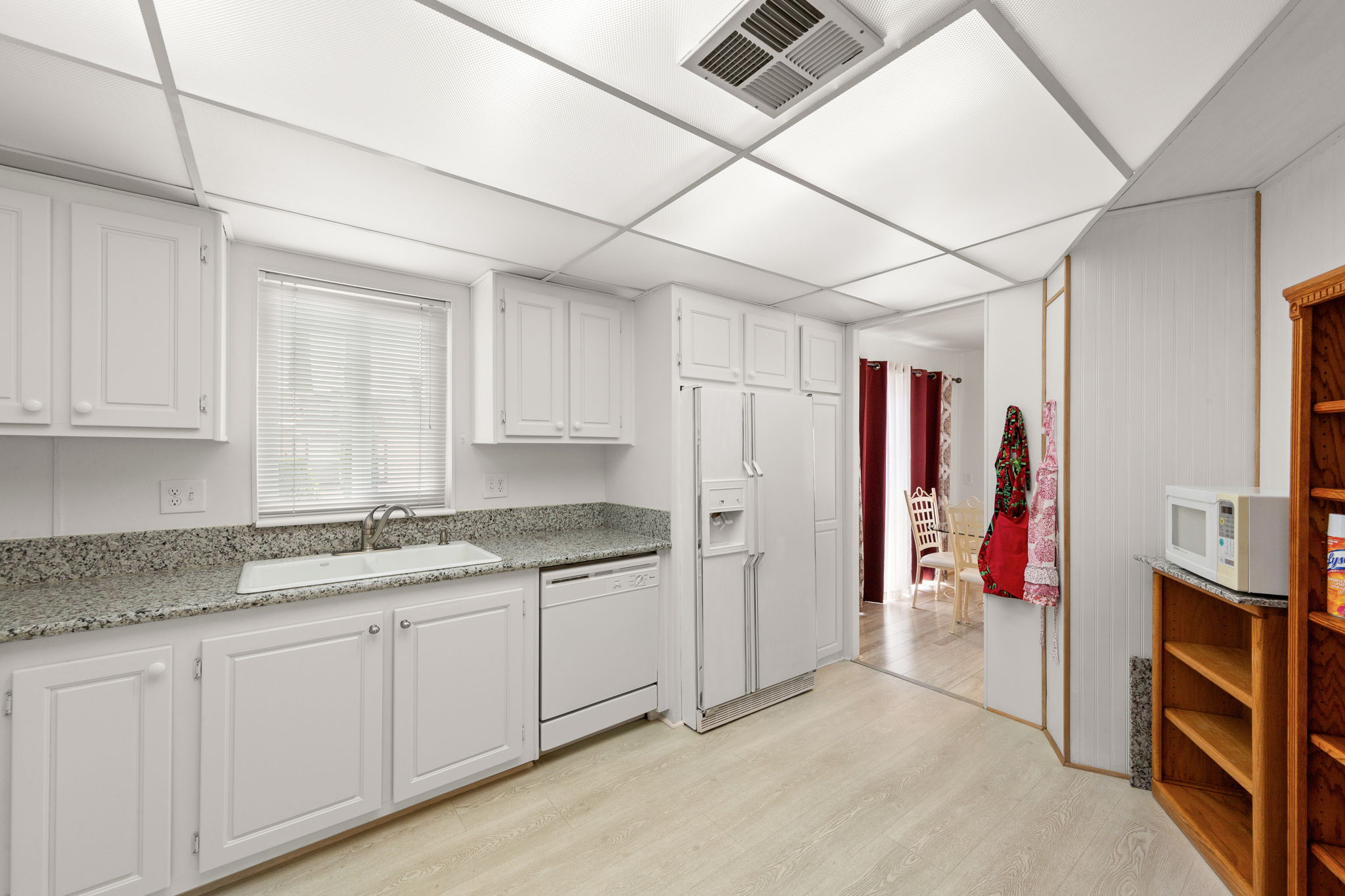 Kitchen featuring white cabinetry, light-toned wood-finish flooring, recessed lighting, a built-in dishwasher, and a window with blinds