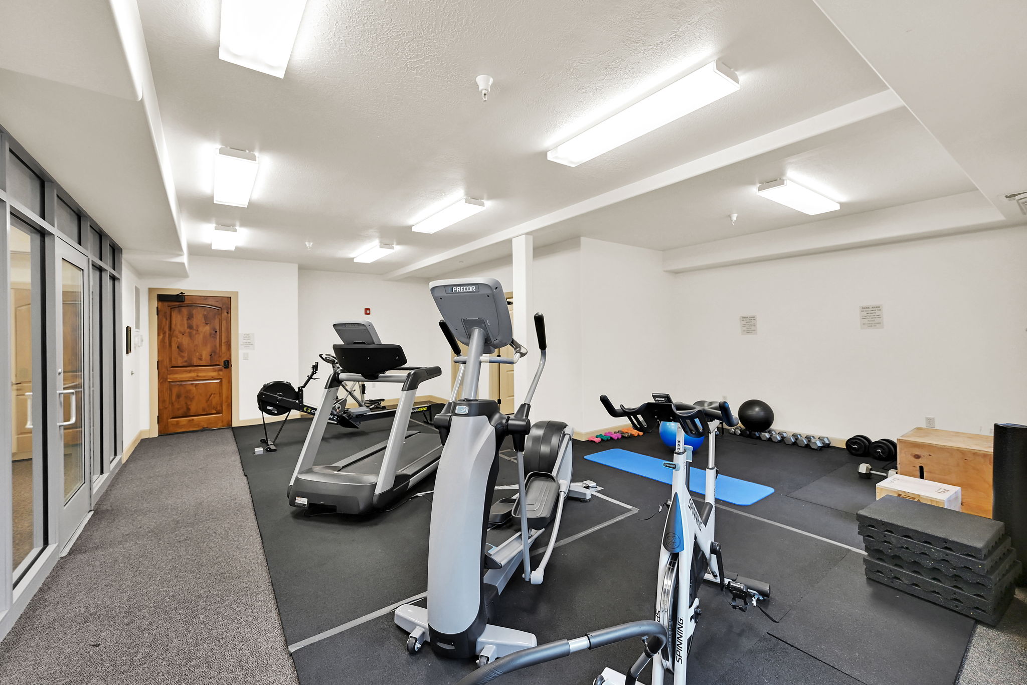 Dedicated fitness space featuring rubber flooring, extensive recessed and surface-mounted lighting