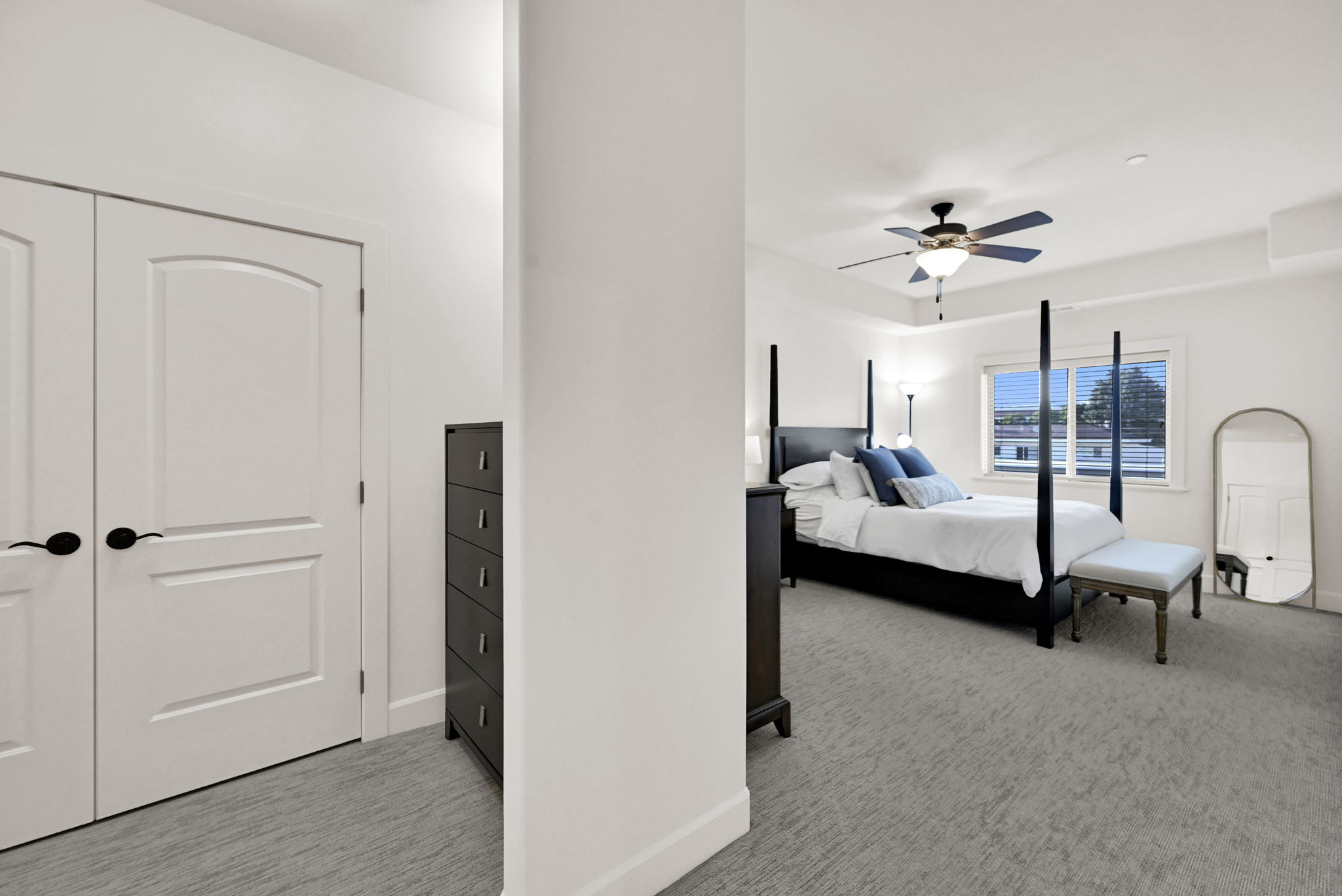 Primary Bedroom: Bright bedroom featuring a tray ceiling with a built-in ceiling fan, two closets, and a large window with blinds