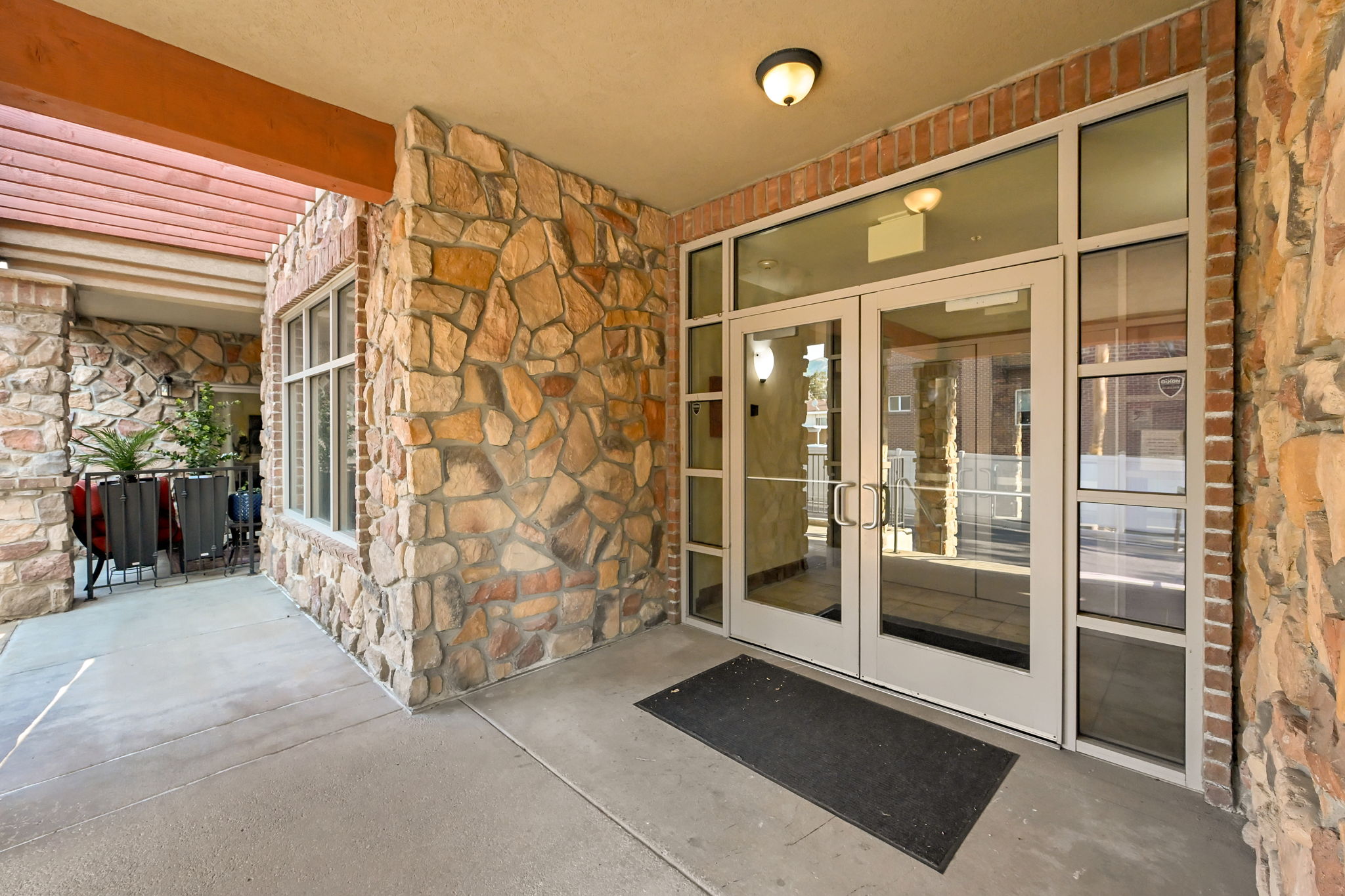 Main Entry Doors: Stone veneer exterior featuring a covered entry, glass double doors, and transom windows