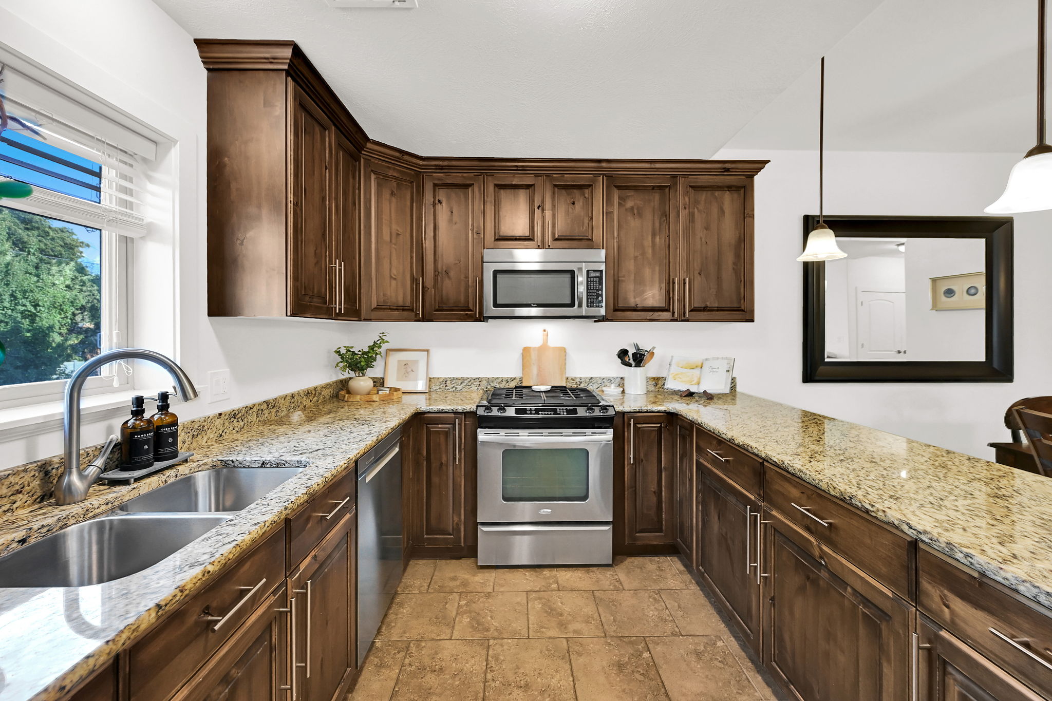 U-shaped kitchen featuring wood cabinetry, light-toned granite countertops, and stainless steel appliances