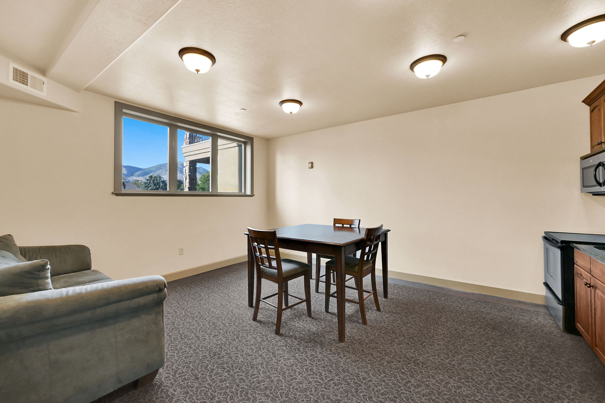 Community Room on Level V: 200  (View): Living area featuring a window with a mountain backdrop, patterned carpet, recessed lighting, and a compact kitchen area with wood cabinetry and stainless steel appliances