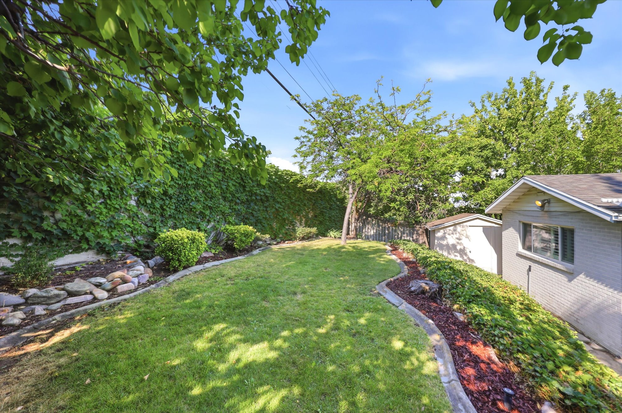 Expansive green lawn framed by mature trees and a vine-covered wall