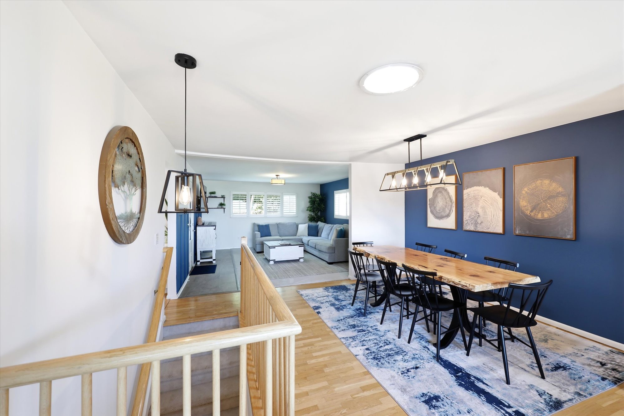 Open-concept living area featuring a prominent dining space with wood-finish flooring and a ceiling-mounted light fixture