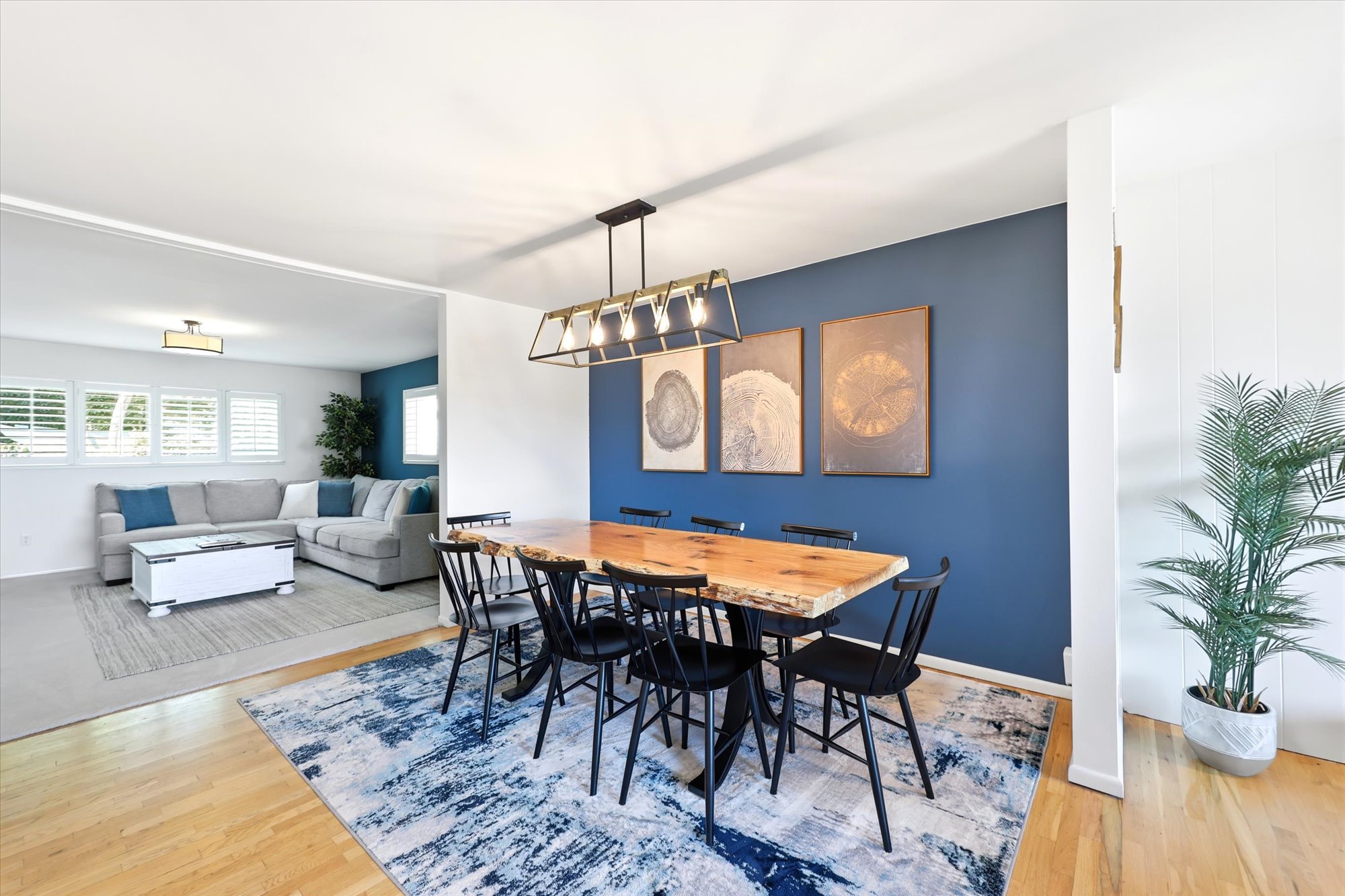 Dining area featuring a live-edge wood table, modern linear chandelier, and a feature wall