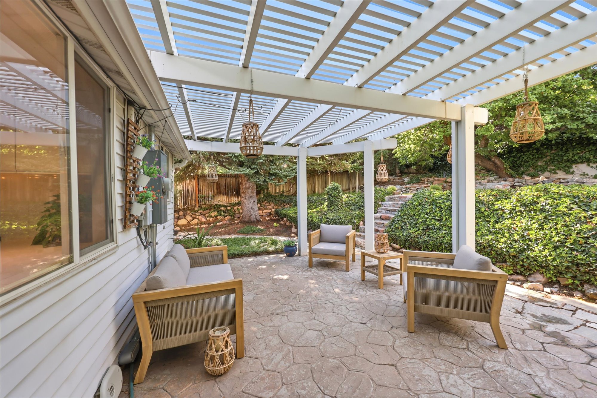 Stamped concrete patio beneath a white slat pergola