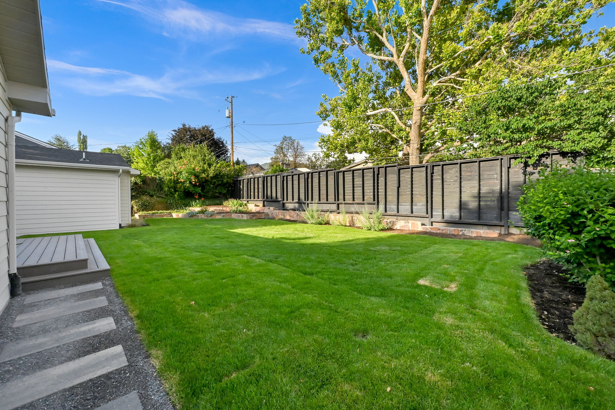 Expansive backyard featuring a manicured lawn, a low-profile composite deck, and a modern privacy fence