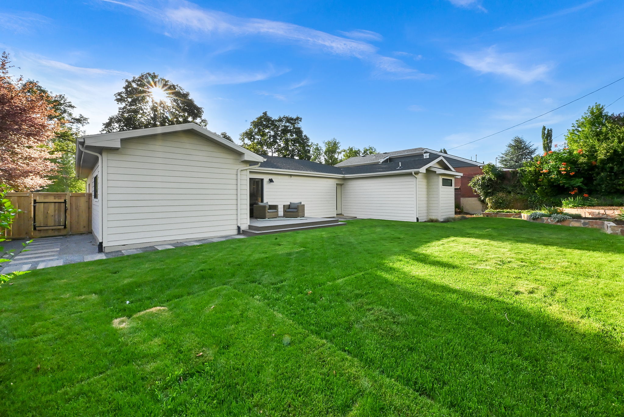 Expansive rear yard featuring green lawn, a deck, and an integrated stone paver walkway