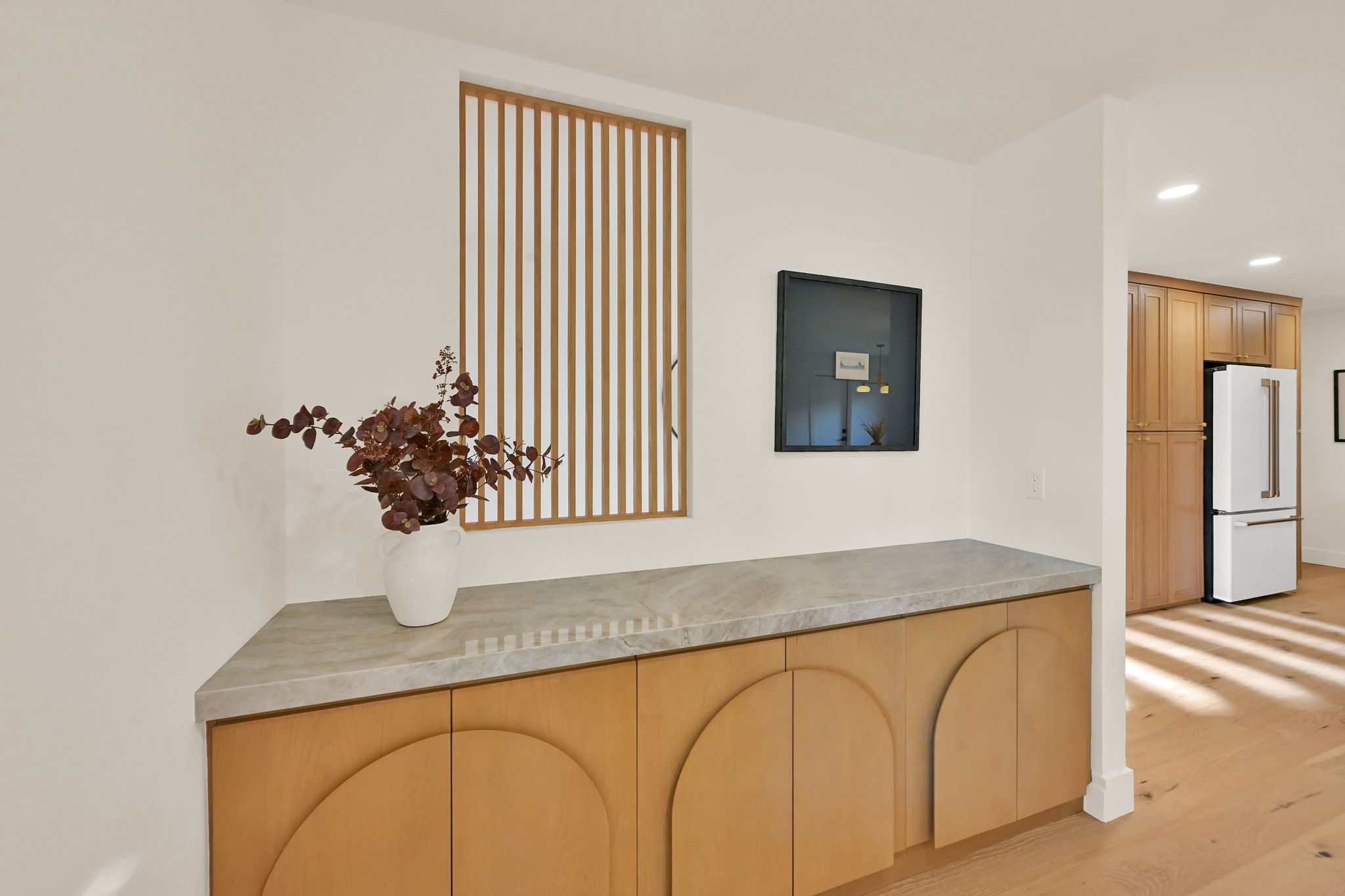 Built-in cabinetry with unique semicircular paneling, a stone countertop, and a slatted wood screen feature