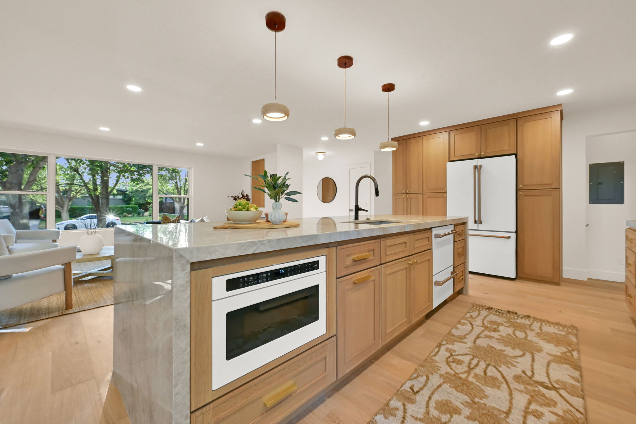 Gourmet kitchen featuring a large island with built-in microwave, integrated dishwasher, and a waterfall-edge countertop