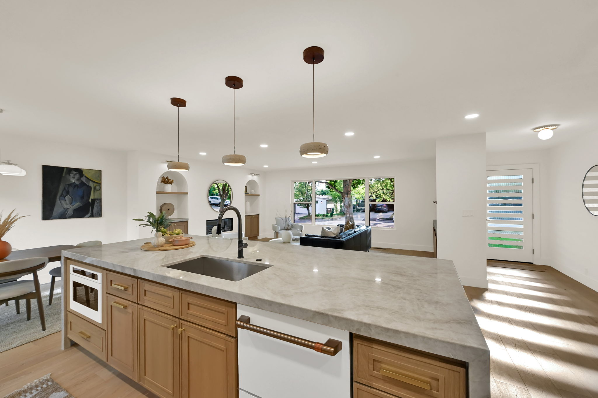 Spacious kitchen island featuring a light-toned stone countertop, and an integrated sink with a matte black faucet