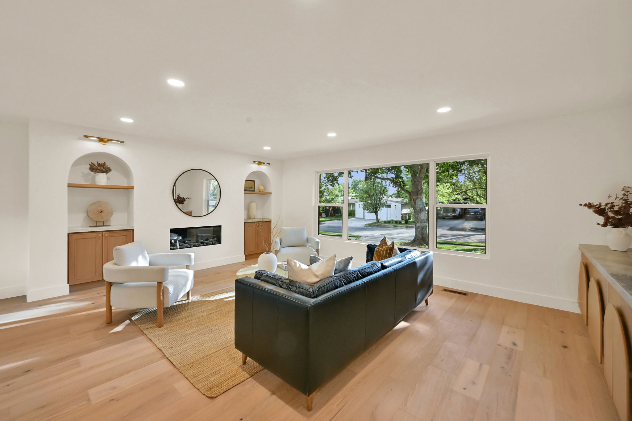 Spacious living area featuring light wood-finish flooring, a contemporary fireplace, and recessed lighting