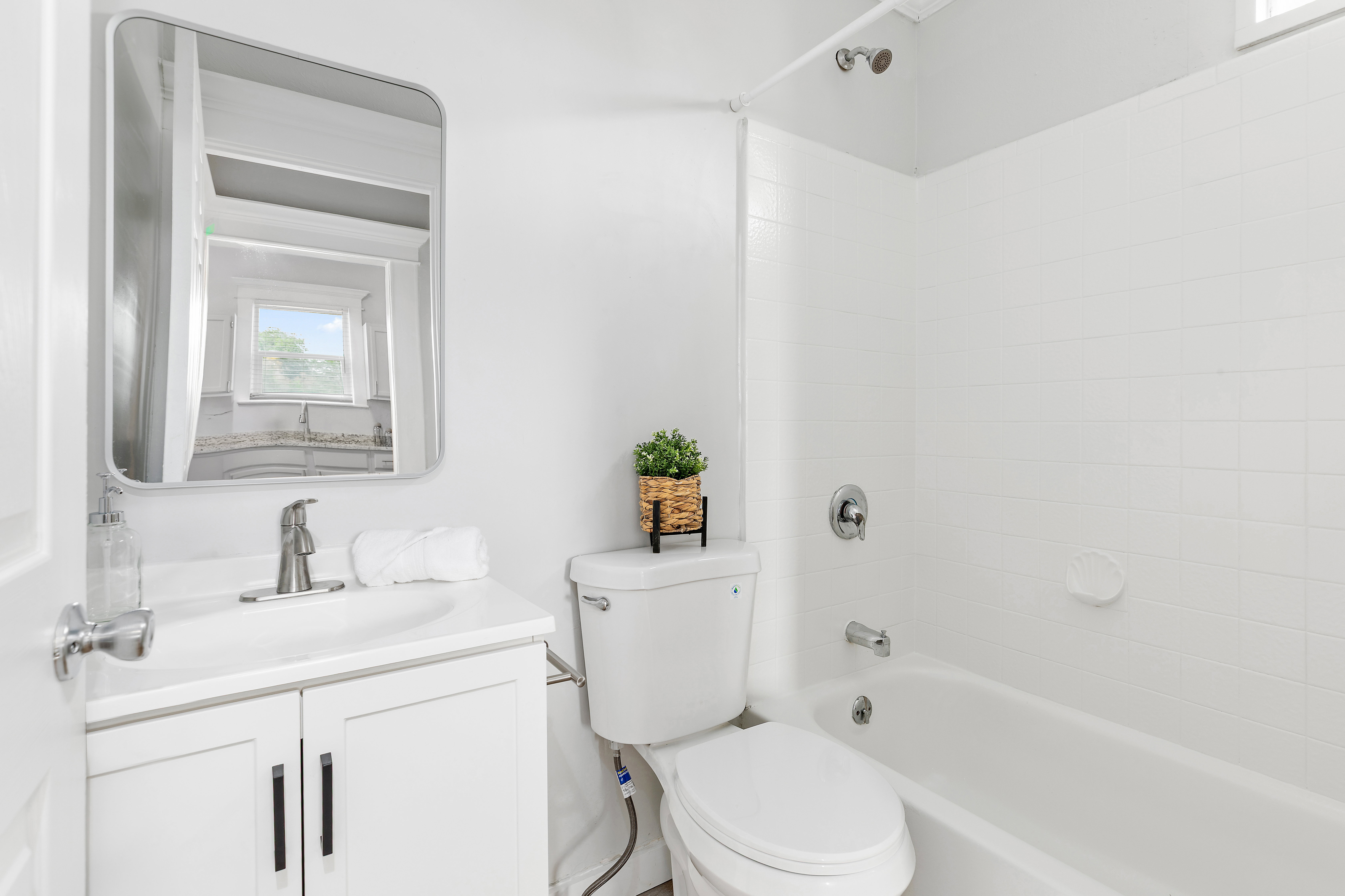 Bathroom featuring a white vanity with an integrated sink, brushed nickel faucet, and a rectangular mirror