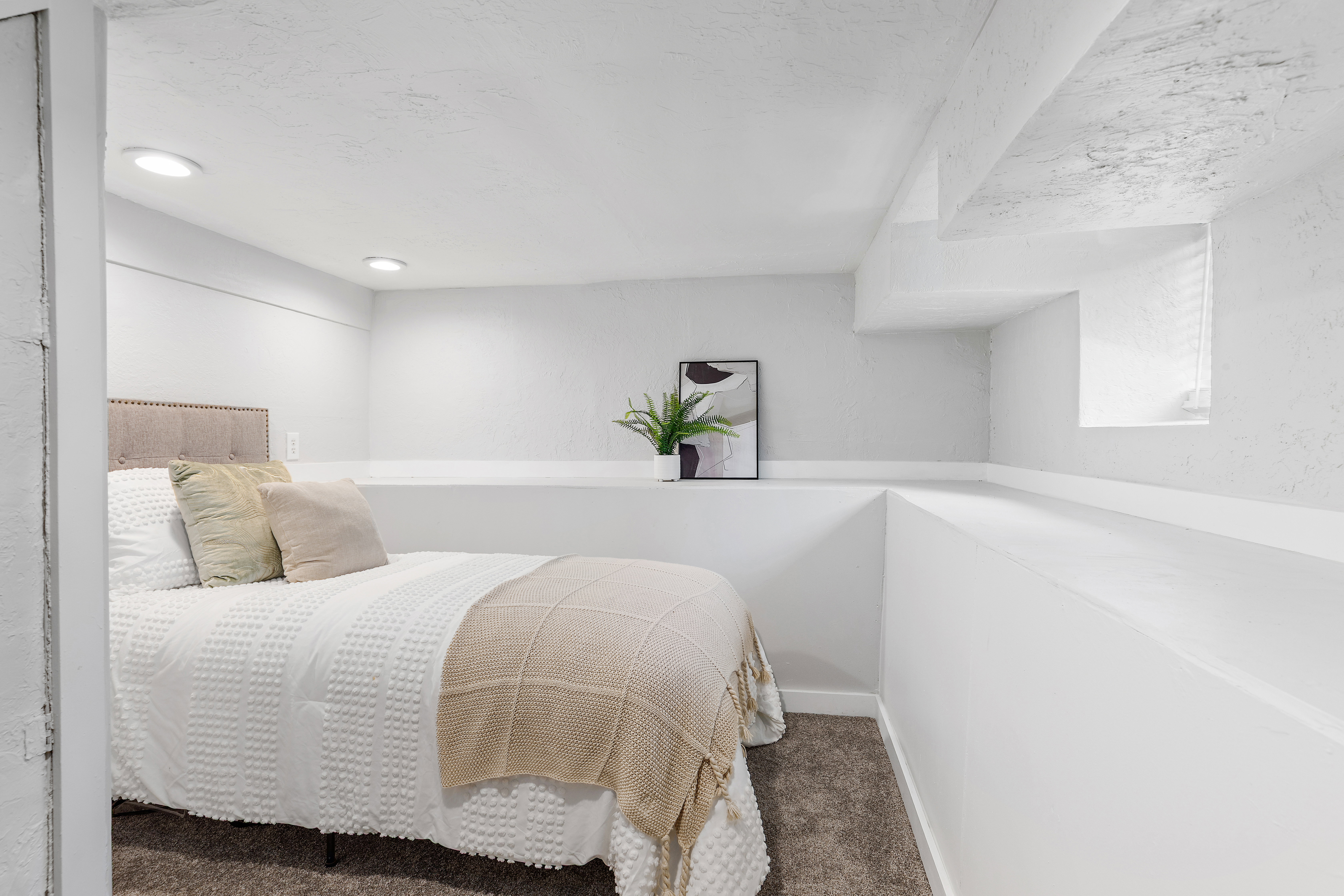 Recessed lighting illuminates this room featuring white painted walls, a built-in ledge, and carpet flooring