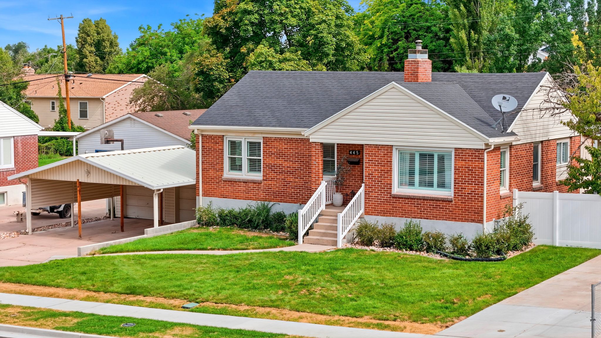Brick exterior with white trim, featuring a dark shingle roof and a prominent brick chimney