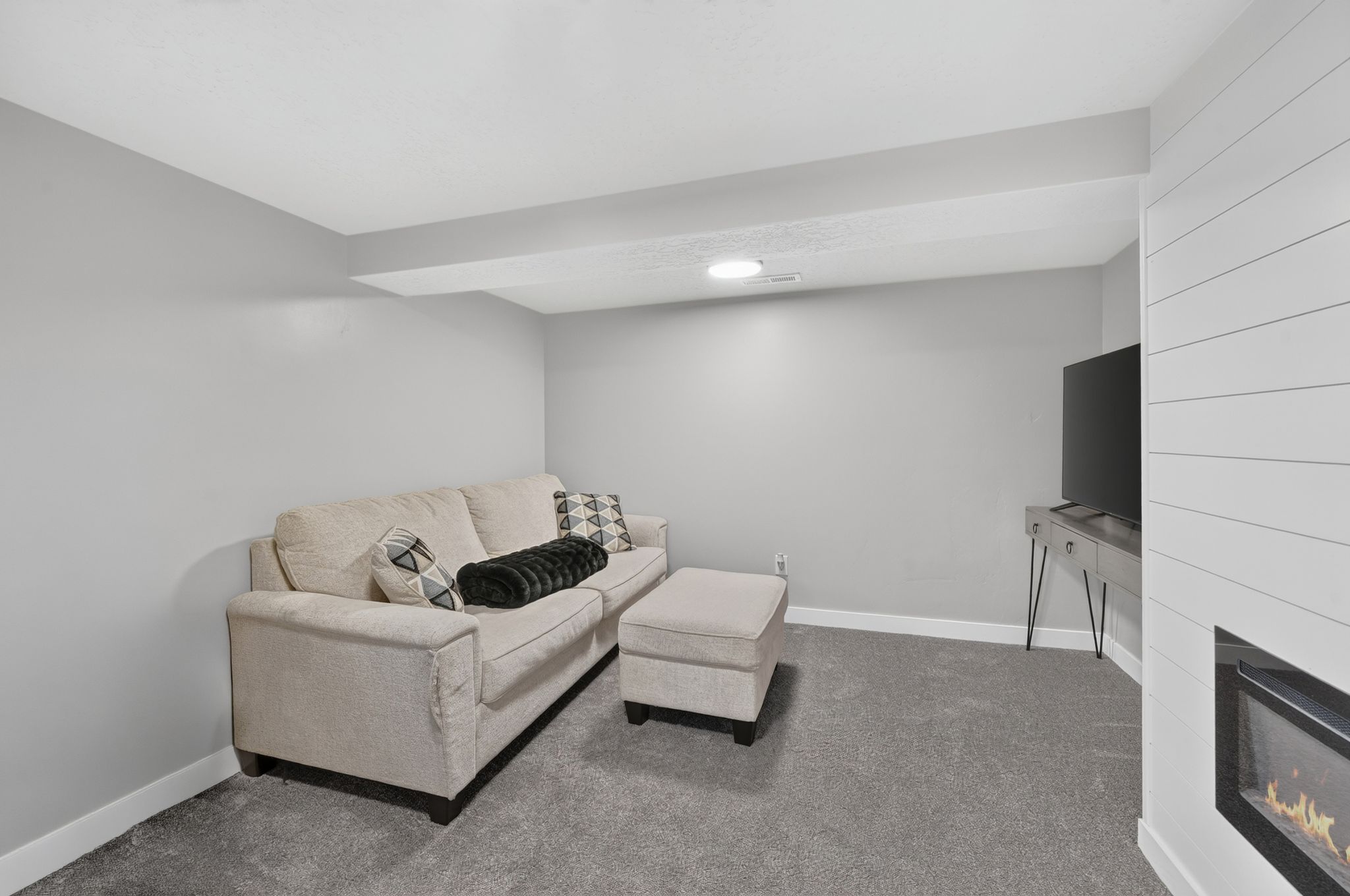 Carpeted room featuring light gray walls, a built-in electric fireplace with shiplap-style surround, and recessed lighting