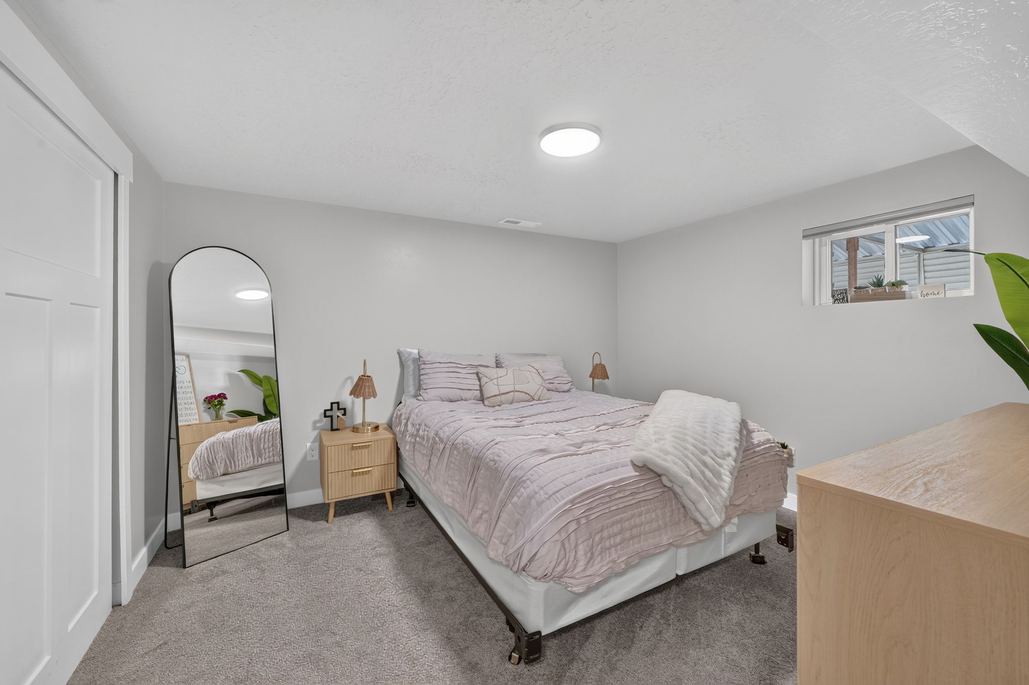 Carpeted room featuring a window with horizontal blinds, a flush-mount ceiling light, and a built-in closet with sliding panel doors
