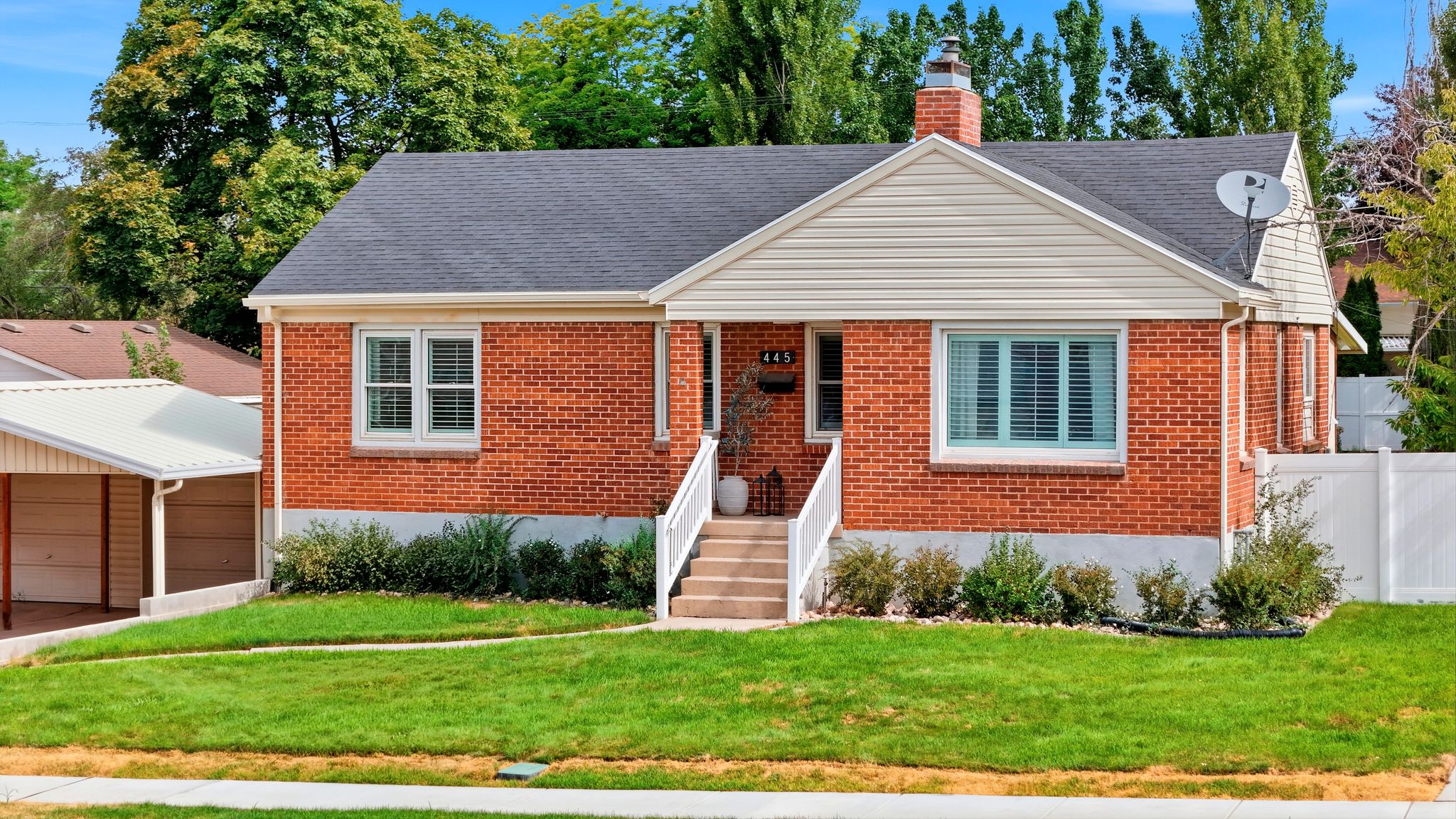 Brick exterior home featuring a well-maintained lawn and mature landscaping