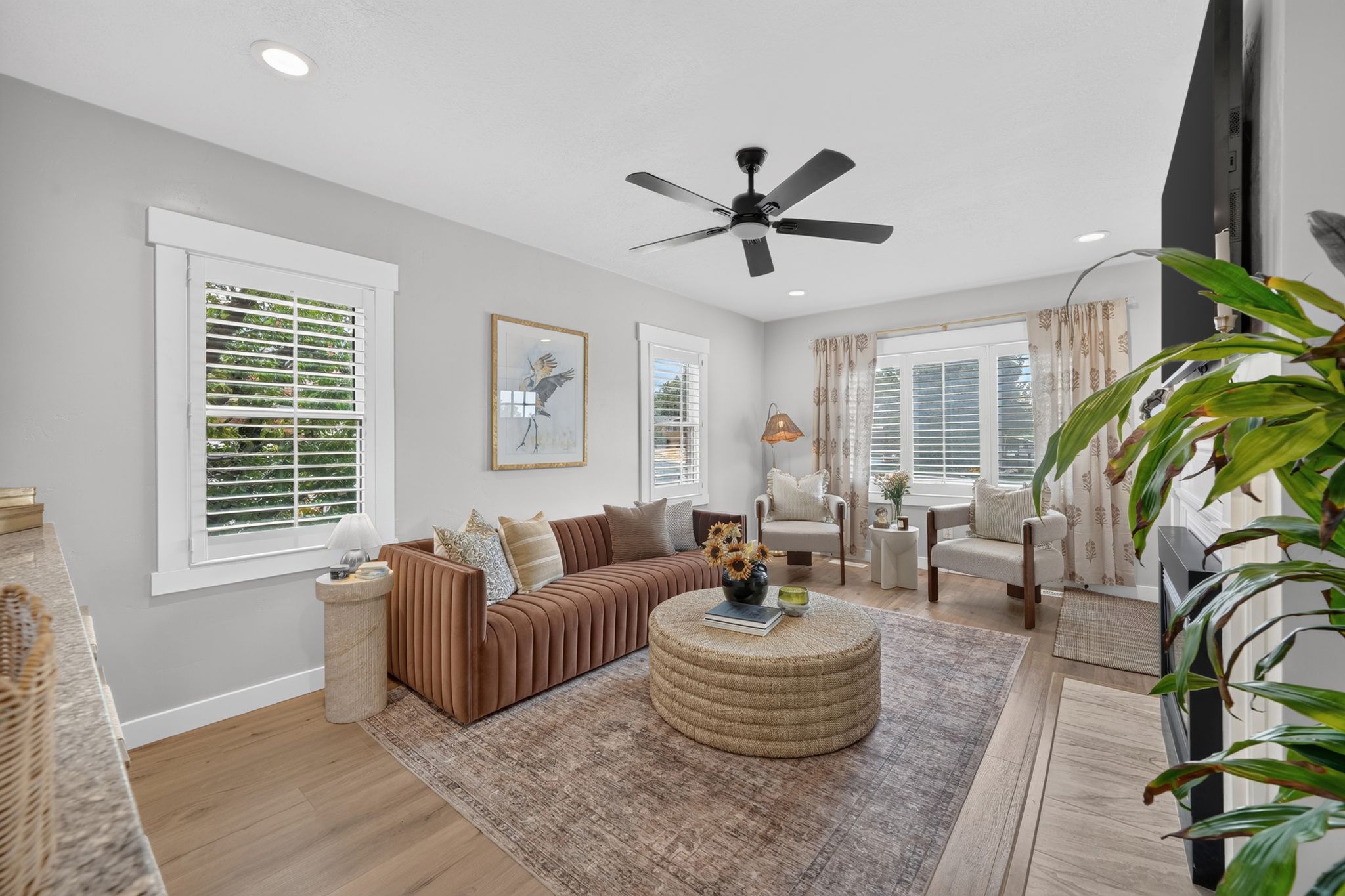 Spacious room featuring light-toned walls, wood-finish flooring, recessed lighting, and a ceiling fan