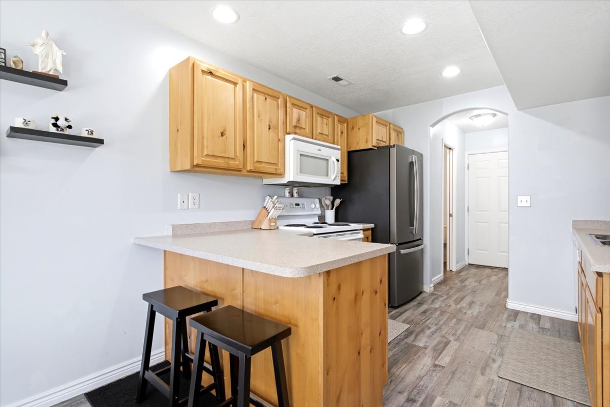 Kitchen featuring wood cabinetry, light-colored countertops, and wood-finish flooring