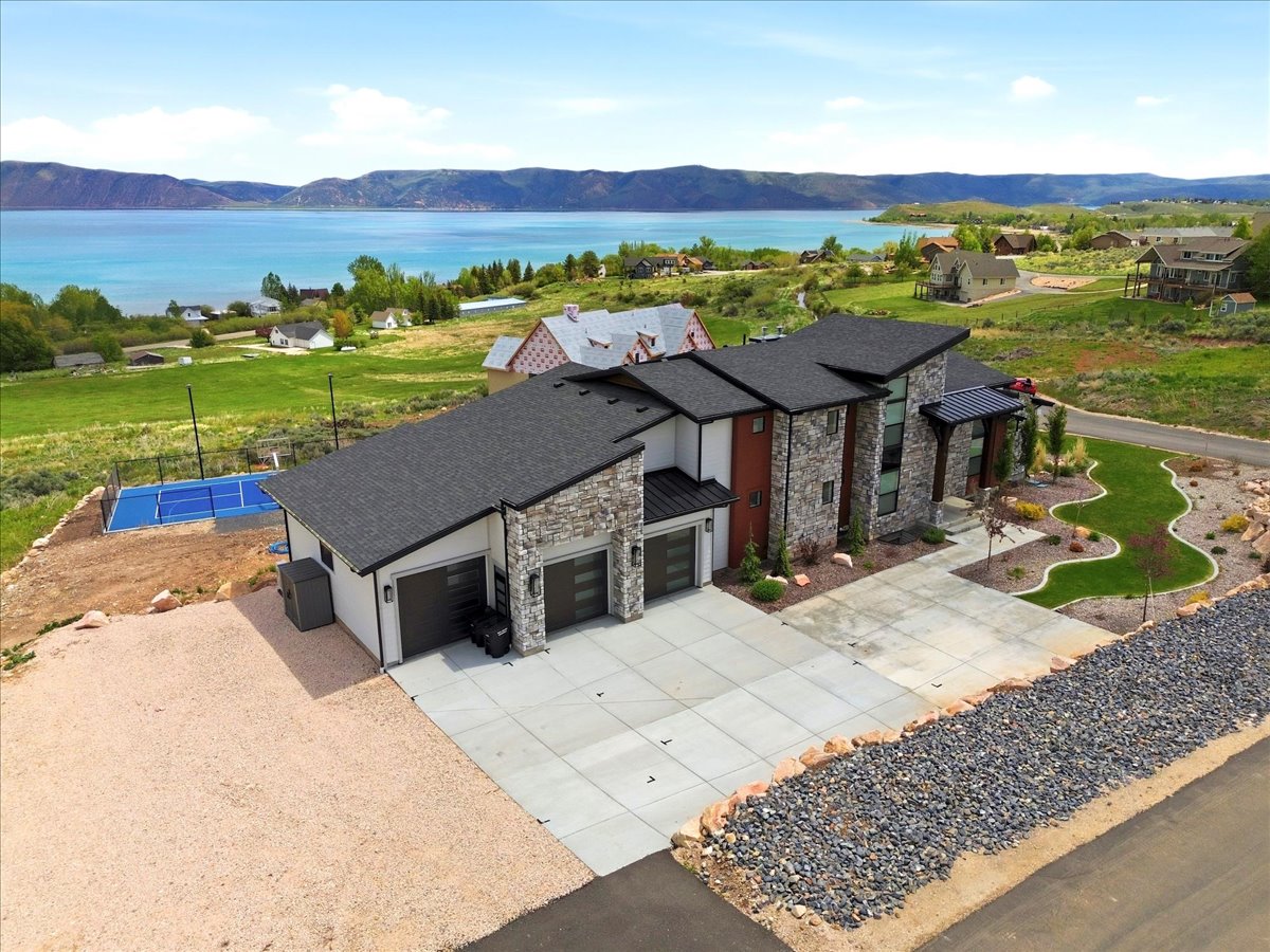 Contemporary residence featuring a stone and stucco exterior, a multi-car garage, and a large concrete driveway