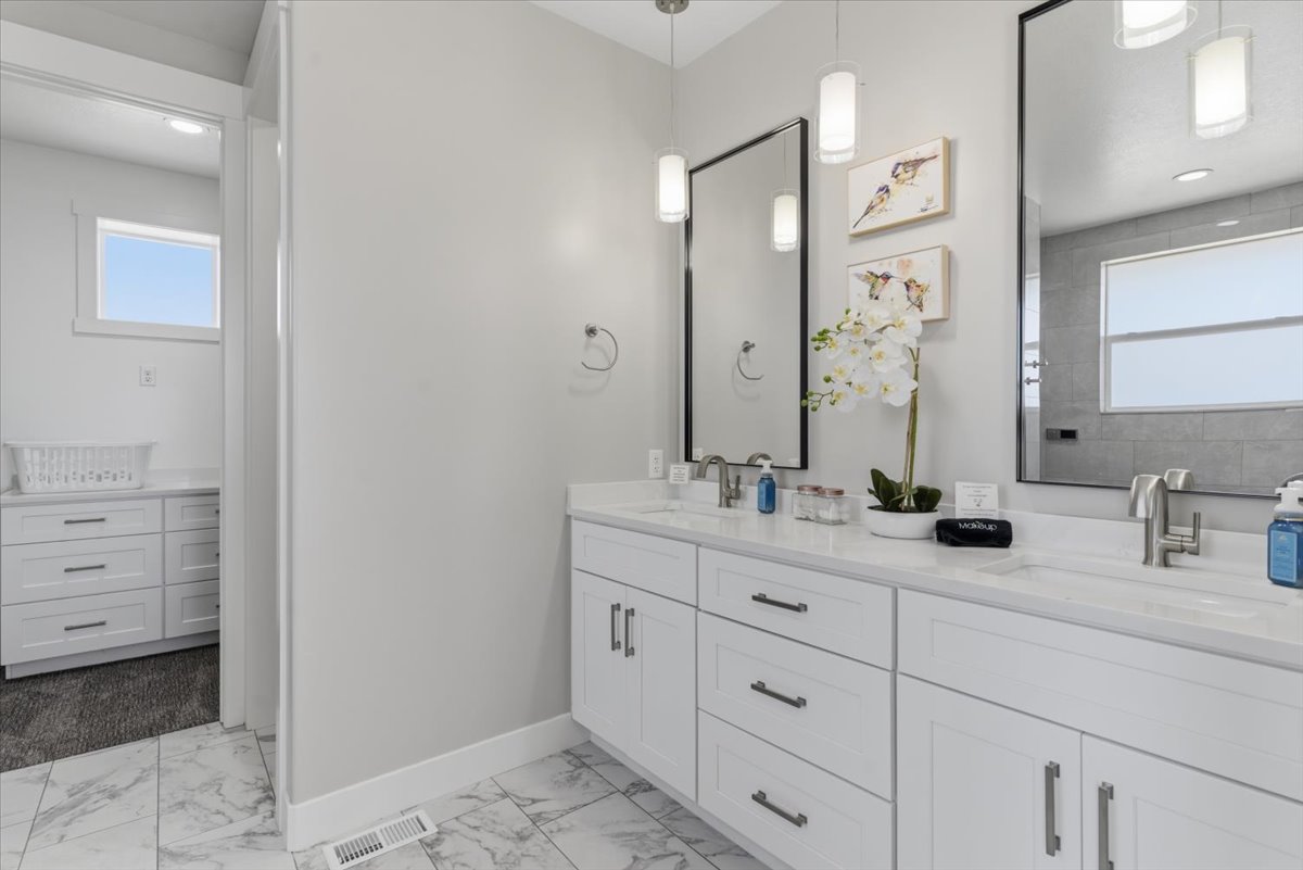 Bathroom featuring a dual vanity with white cabinetry, white countertops, and brushed nickel hardware