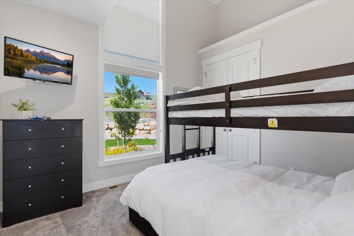 Room featuring a built-in bunk bed, carpeted flooring, and a large window with transom